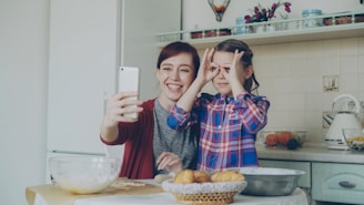 Mother and daughter take a silly selfie in the kitchen.