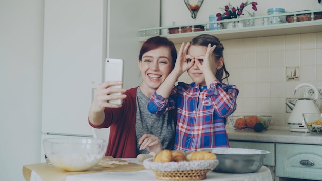 Mother and daughter take a silly selfie in the kitchen.