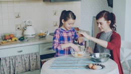 Two girls are cooking together in the kitchen.