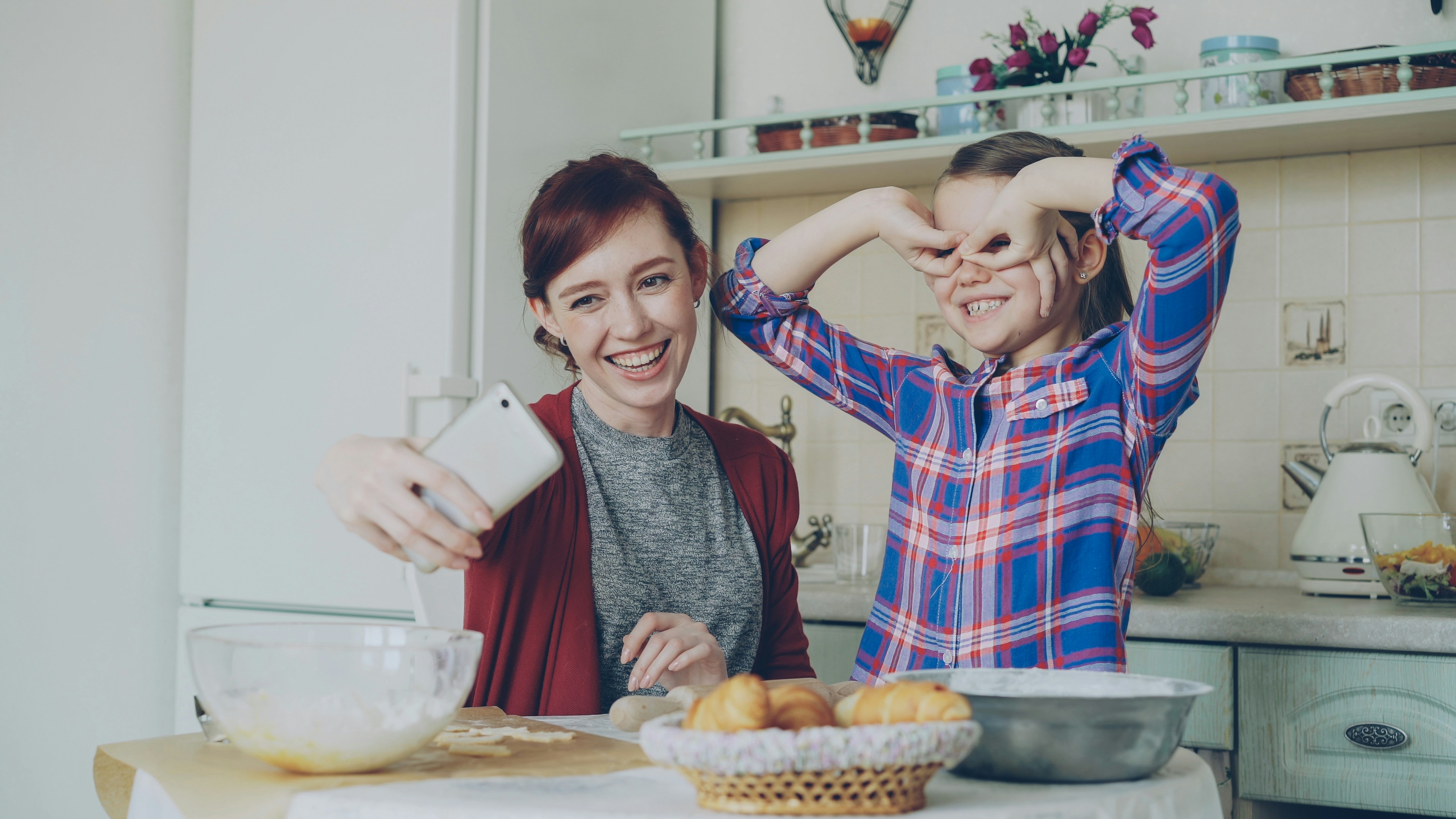 Mother and daughter pose for a fun selfie in the kitchen.