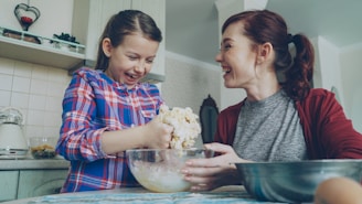 Mother and daughter bake together, laughing.
