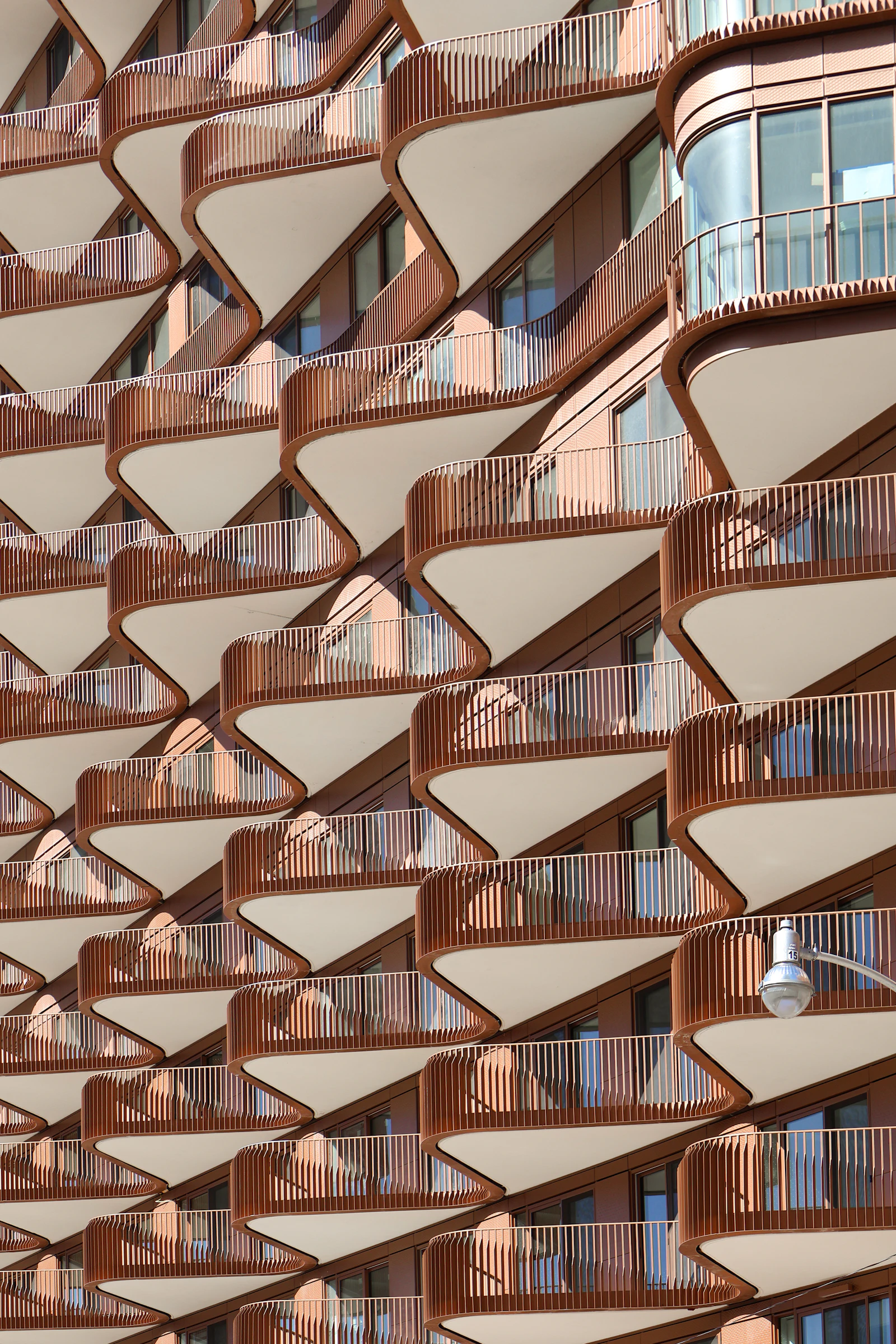 A modern Toronto apartment building with curved stacked wooden balconies seen from below