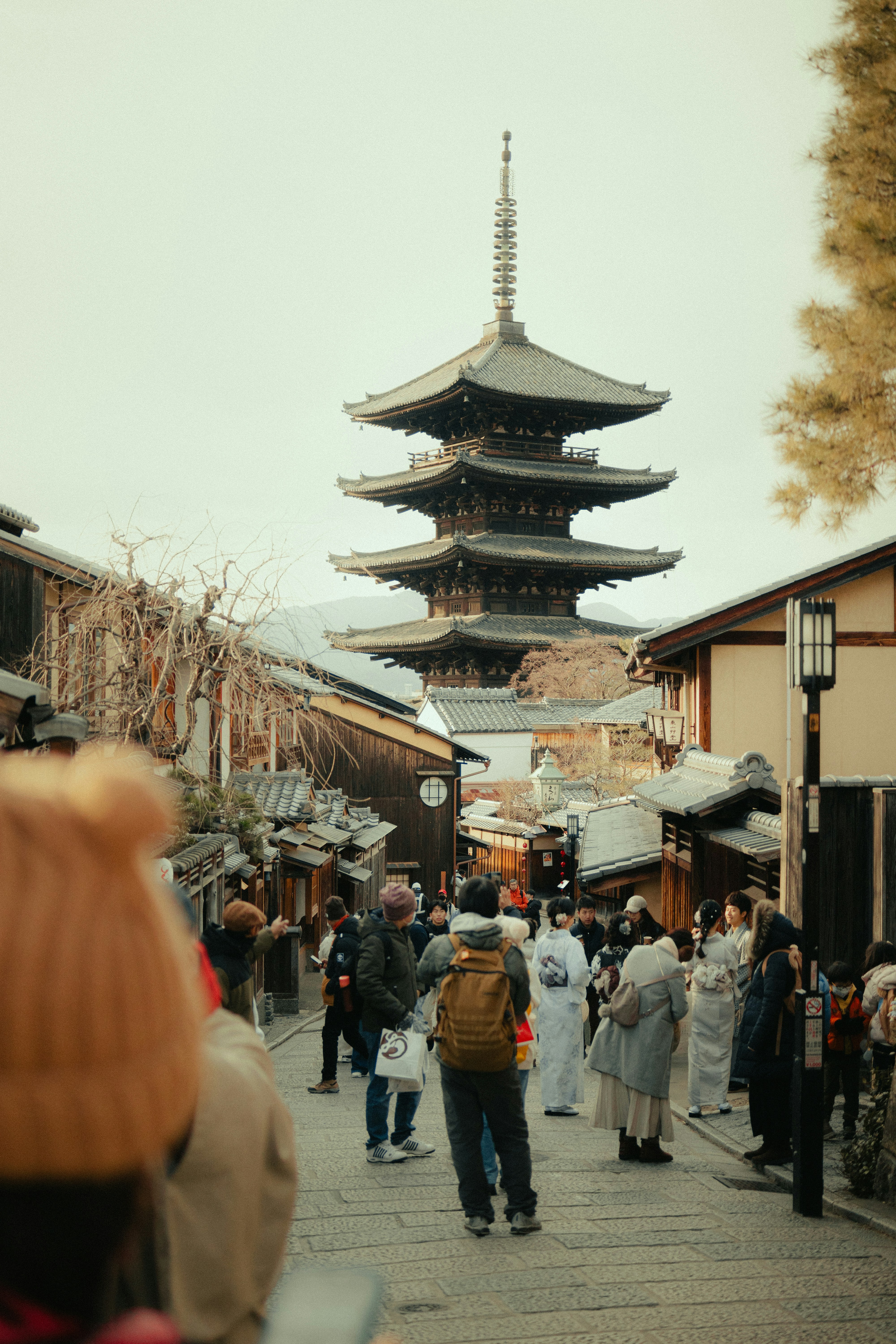 People walk on a street near a traditional japanese pagoda.