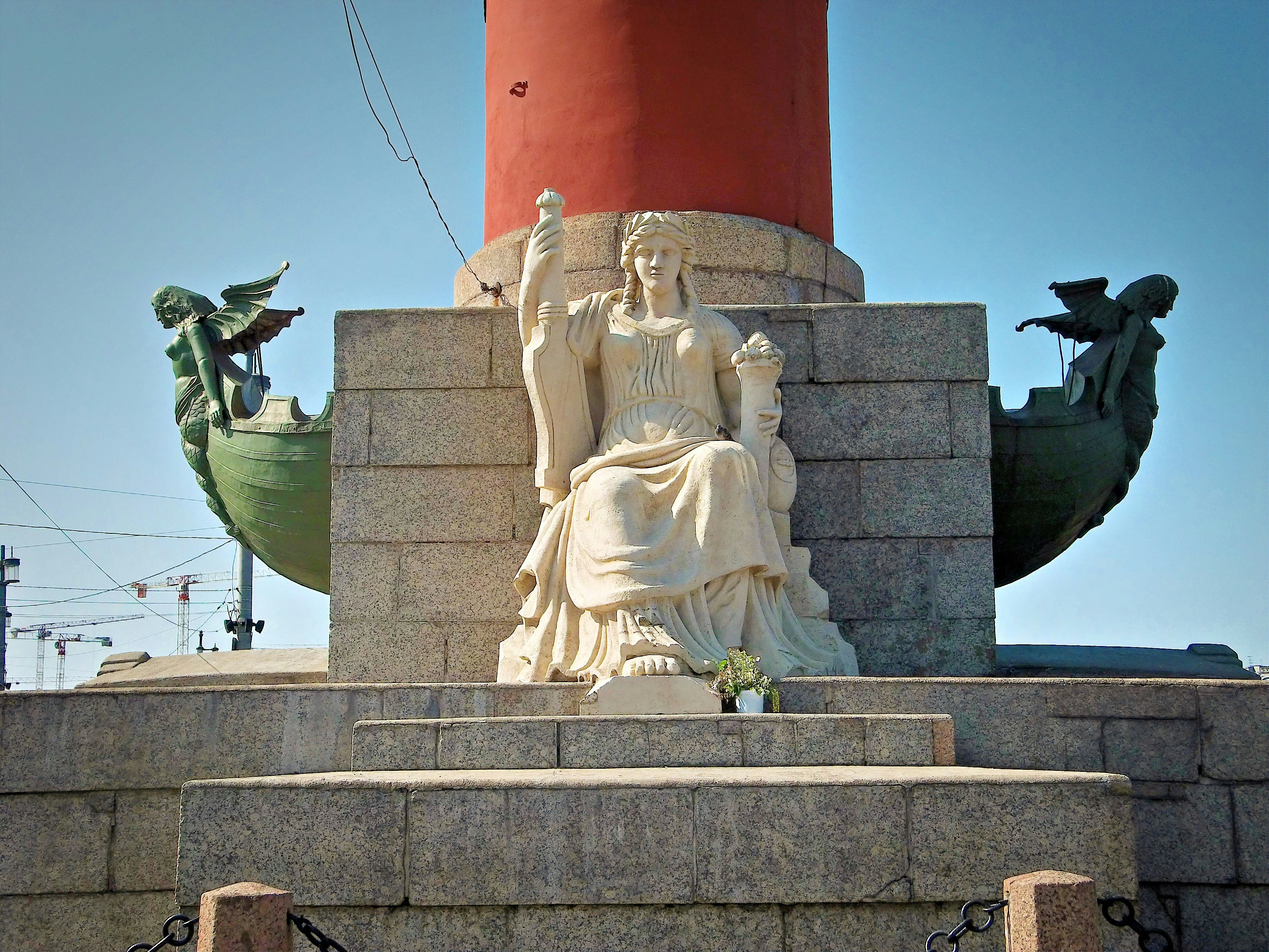 A statue stands near a red pillar.