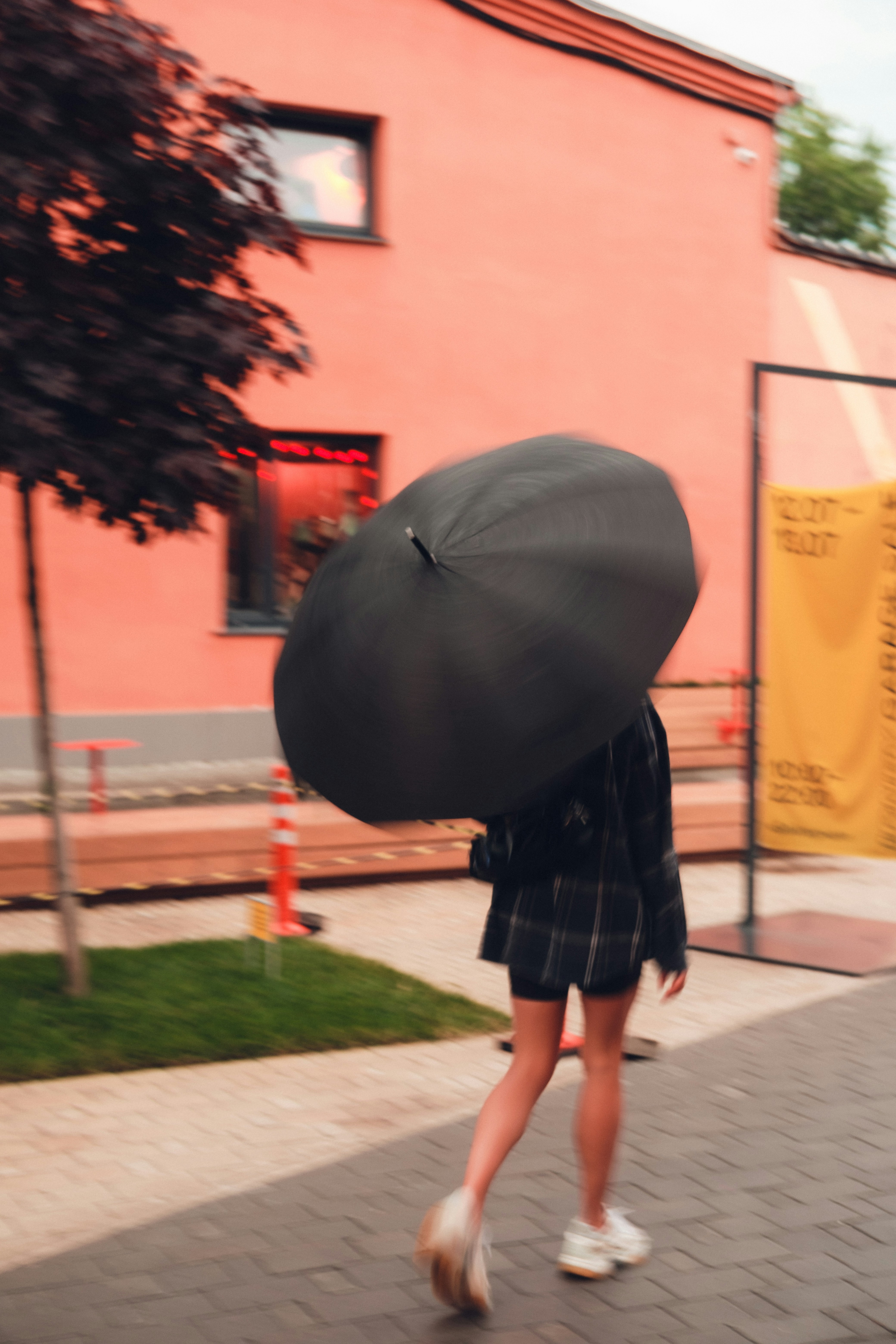 A person walks with an umbrella on a windy day.