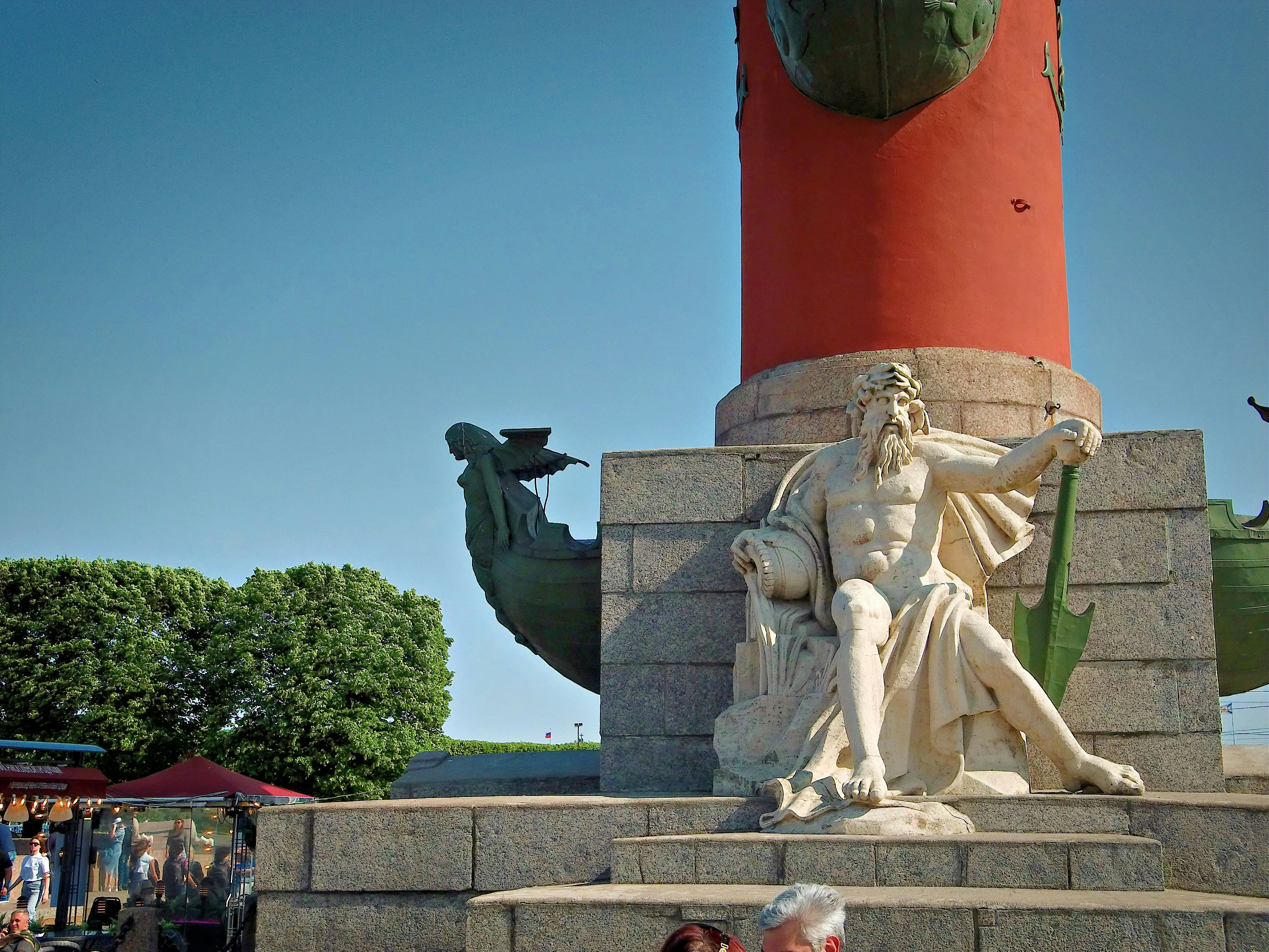 A statue stands below a tall red pillar.