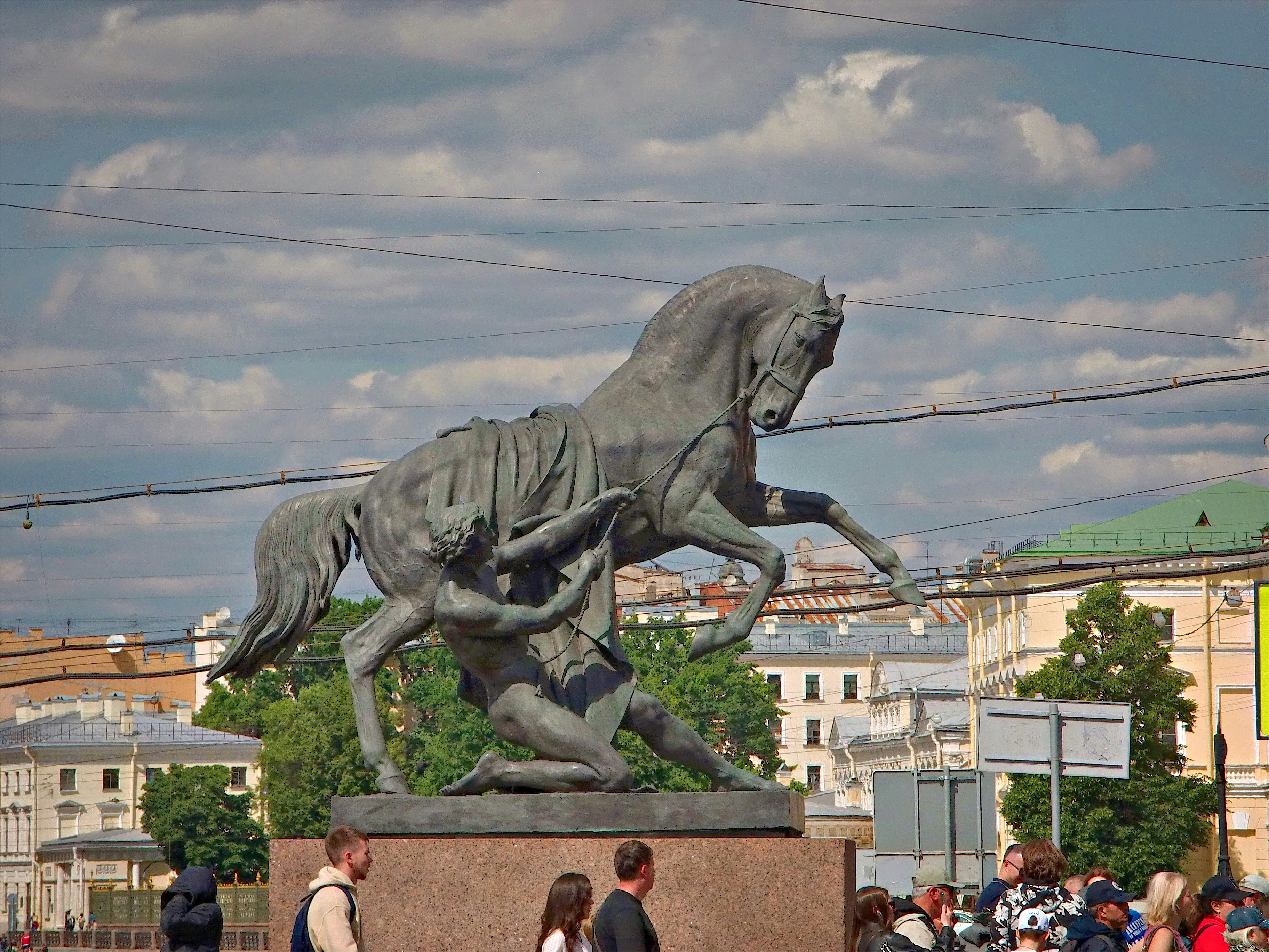 A man is kneeling before a powerful horse statue.
