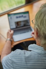 An elderly person is using a laptop.