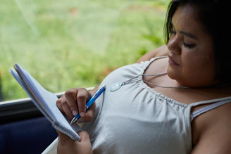 A woman is writing in a notebook.