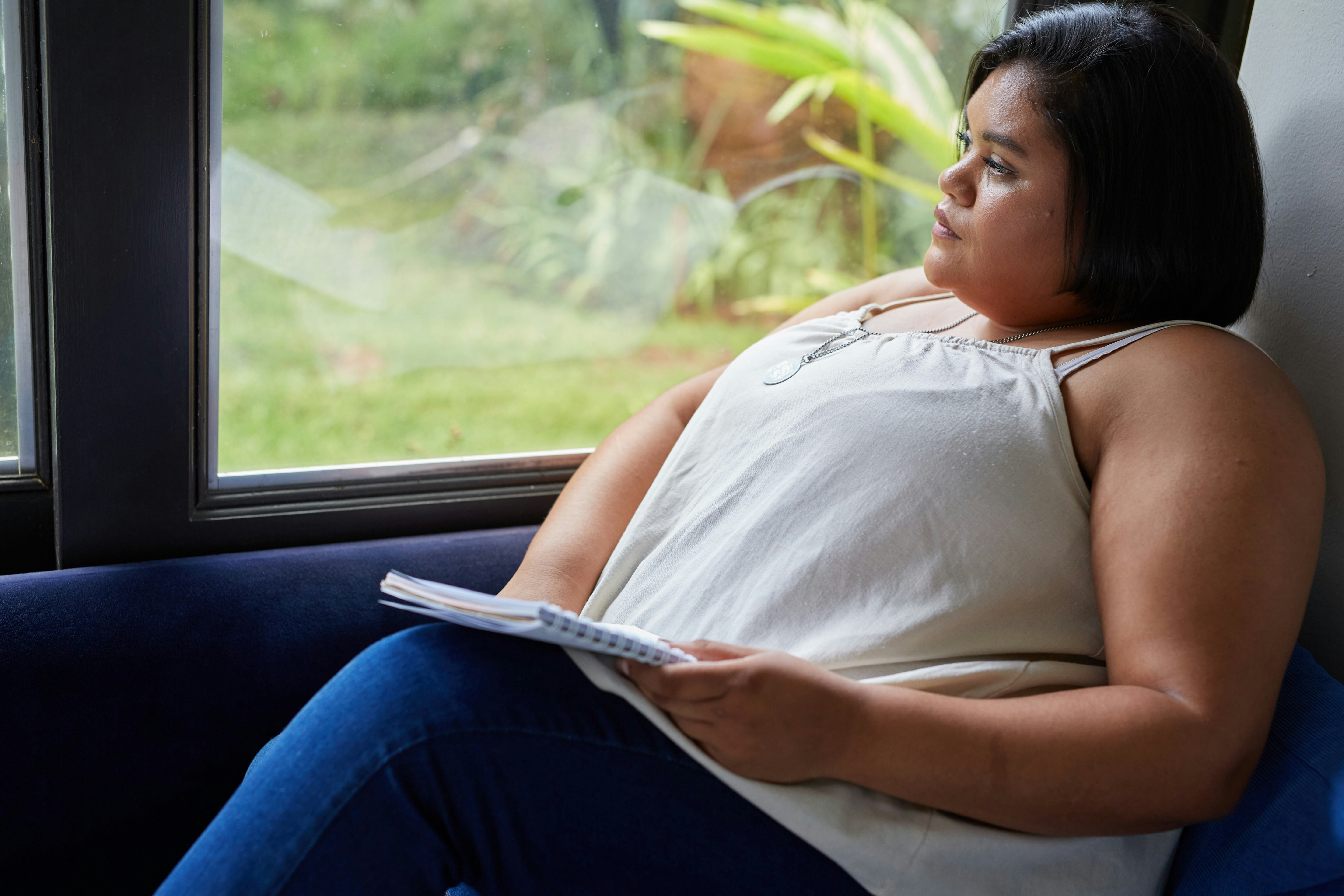 Eine Frau schaut gedankenversunken aus dem Fenster.