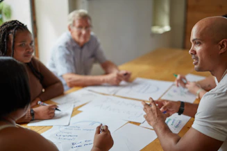 People collaborate around a table with papers.