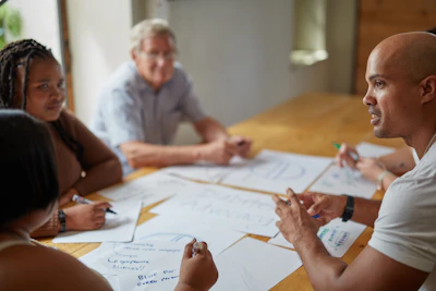 People collaborate around a table with papers.