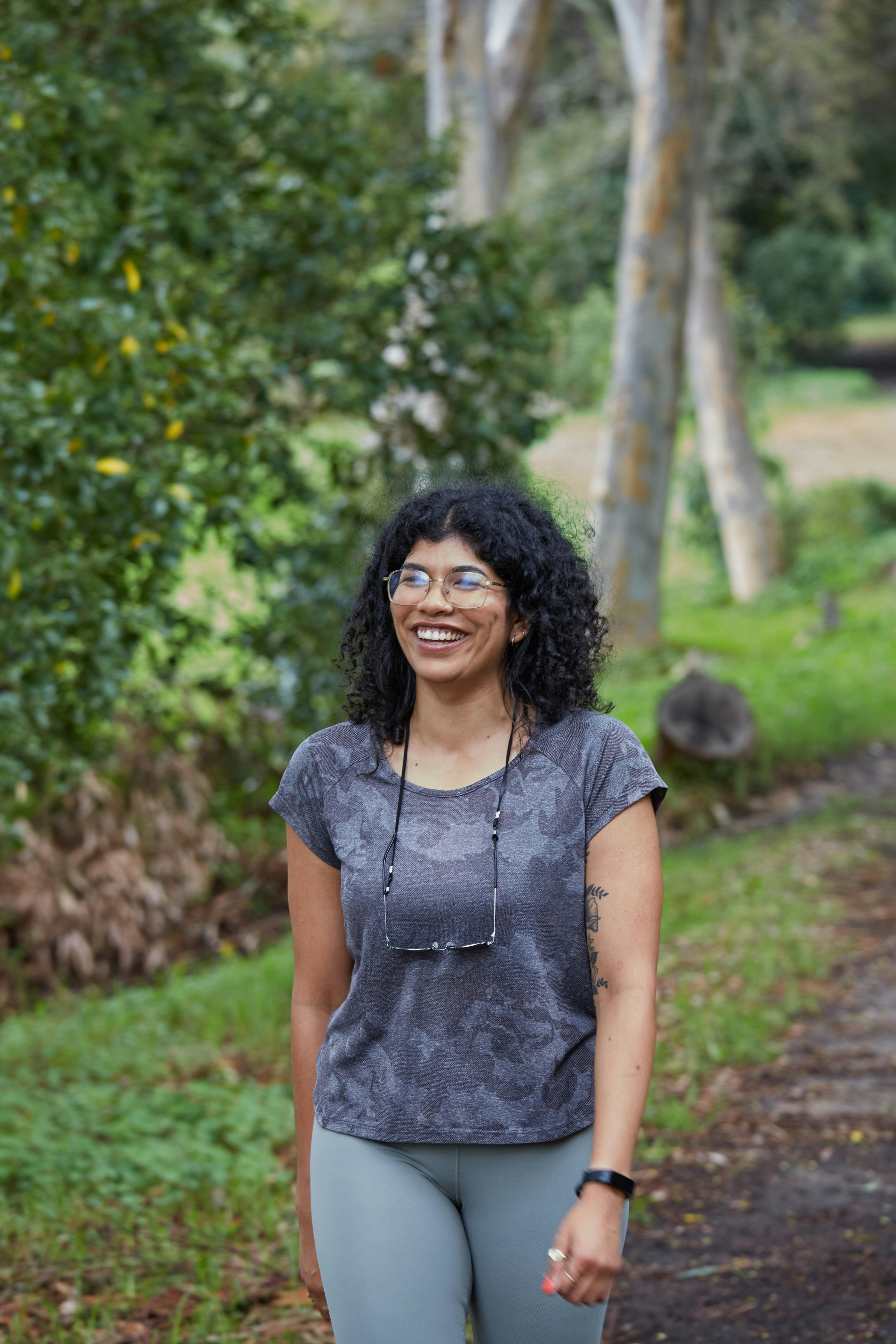 Eine Frau lächelt, während sie in einem Park spazieren geht.