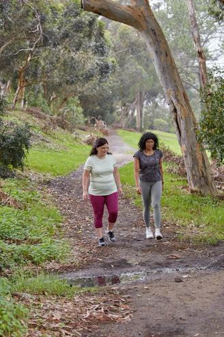 Two women are walking and talking on a trail.