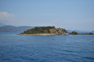 An island sits in the blue ocean waters.