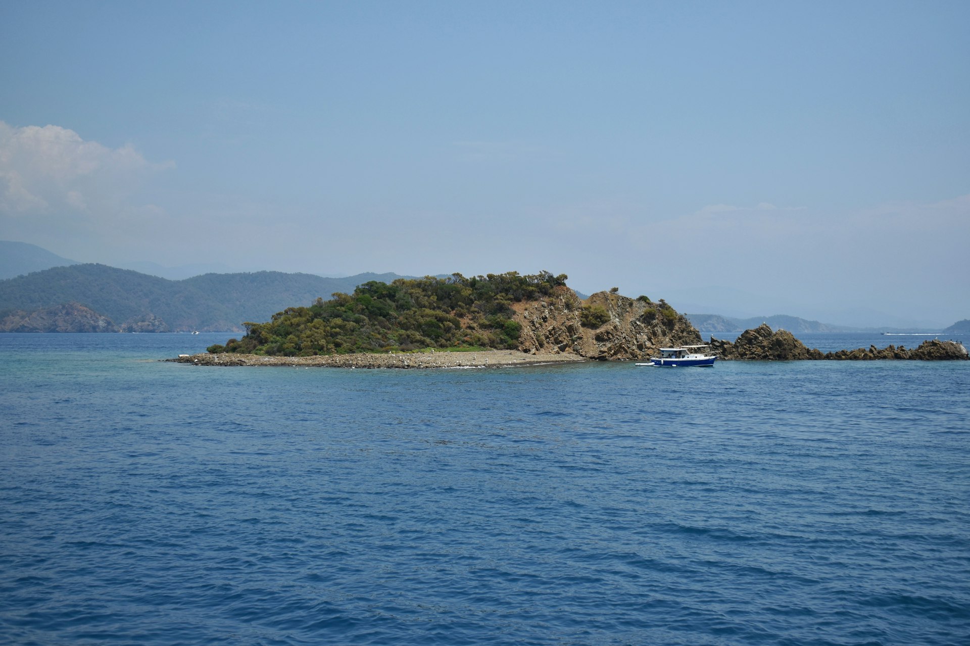 Une île paradisiaque isolée entourée par les eaux turquoises scintillantes de l'océan Atlantique sous un ciel bleu
