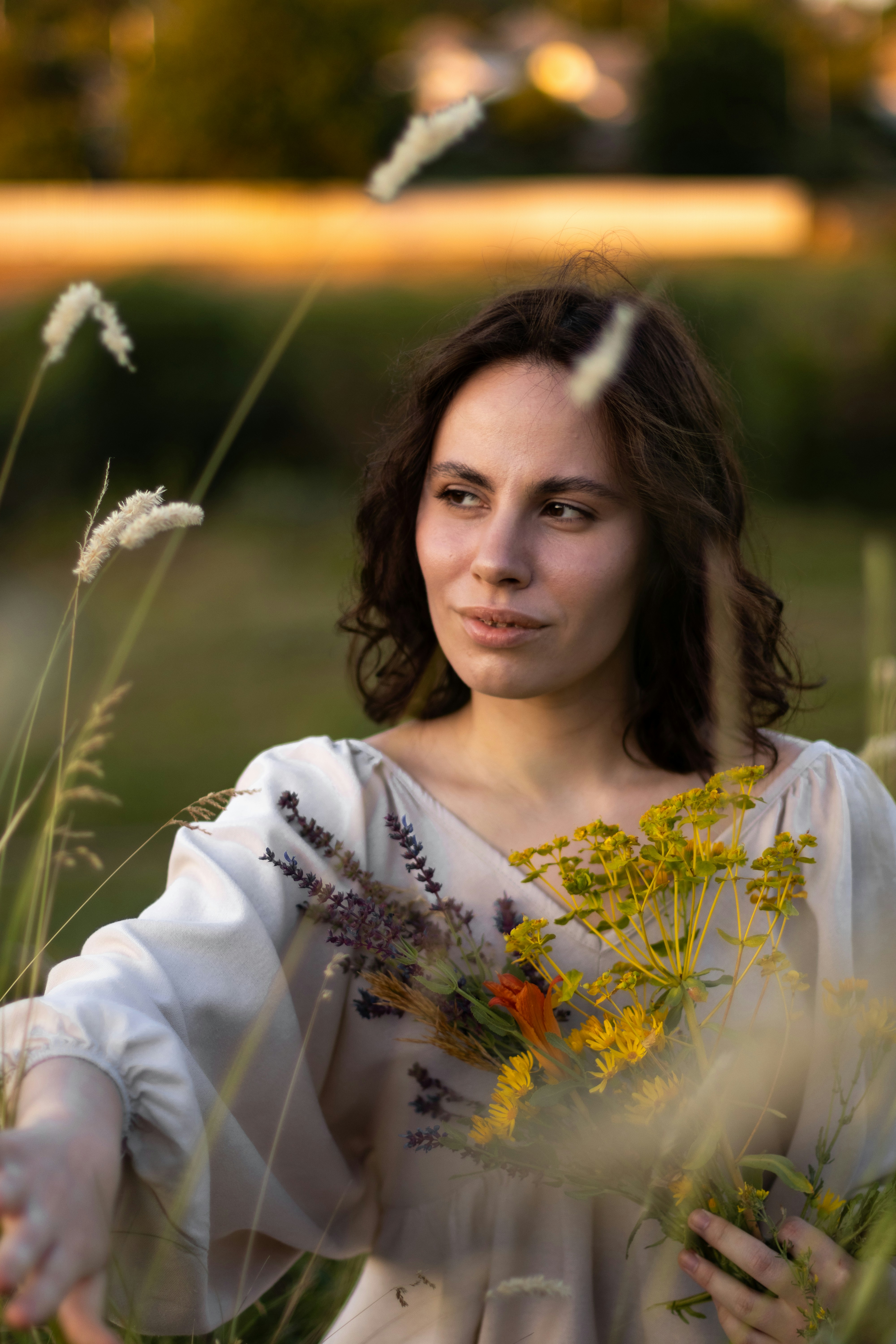 Woman stands in a field, holding flowers.