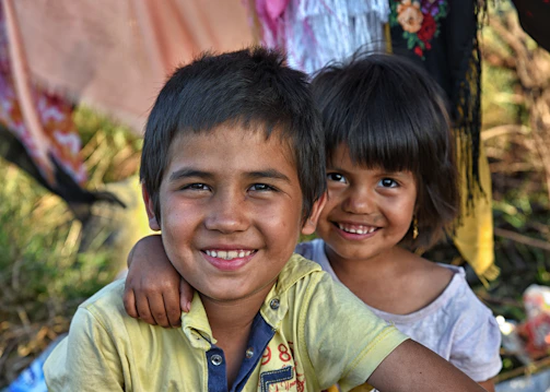 Two smiling children embrace each other joyfully.