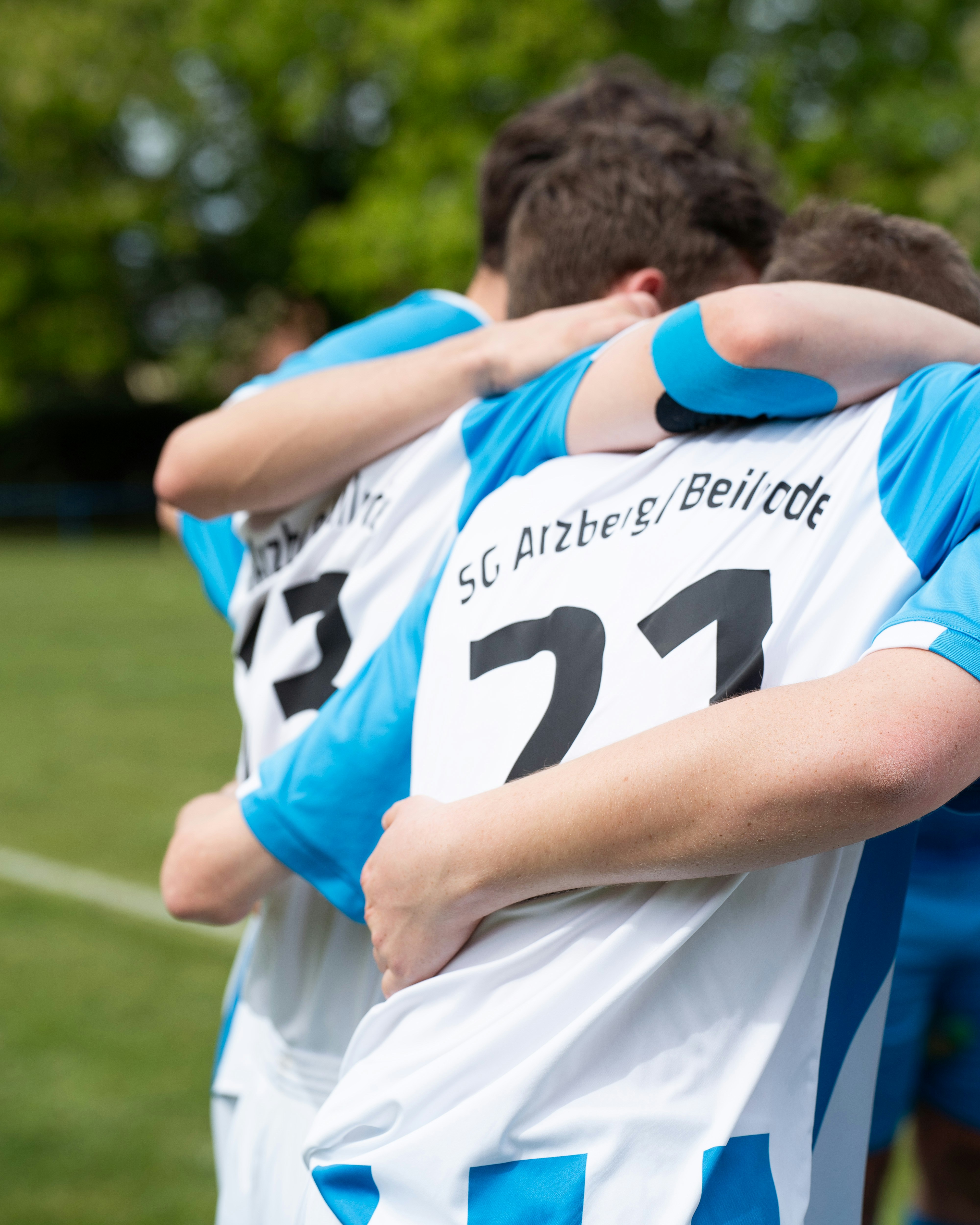 Soccer players celebrate a victory with a team hug.