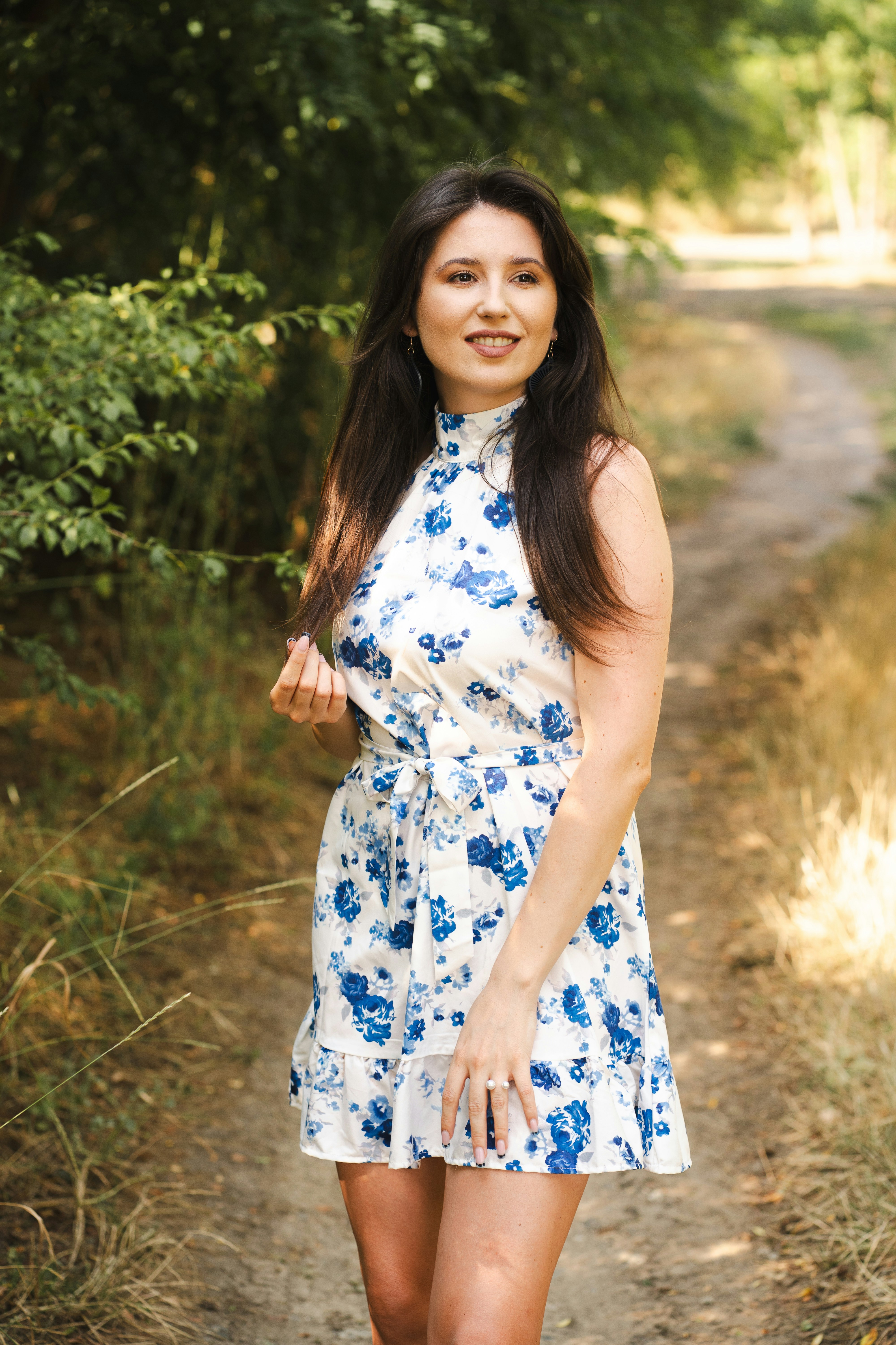 La mujer posa con un vestido floral en un camino.
