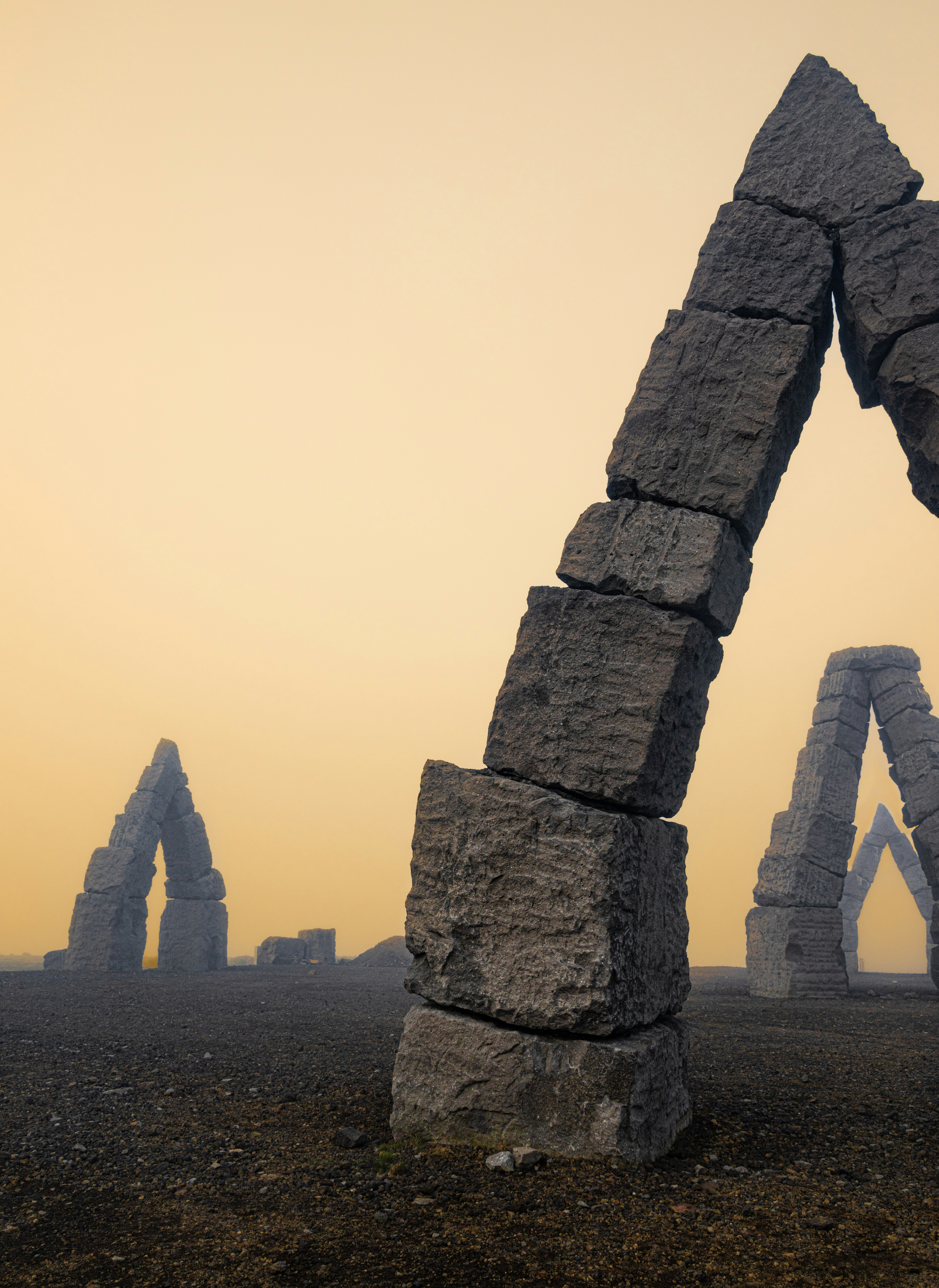 Stone arches stand in a foggy landscape.