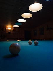 Pool balls rest on a turquoise pool table.