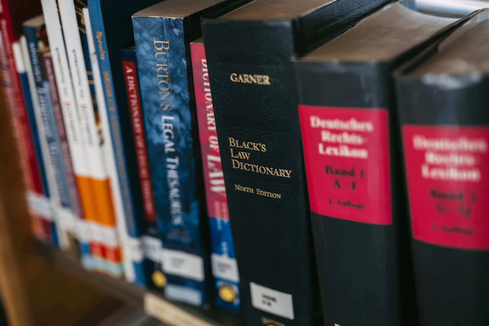 Rows of legal reference volumes on a shelf, including a law dictionary, representing the policy wording now defining what AI-related liability is covered and what is excluded