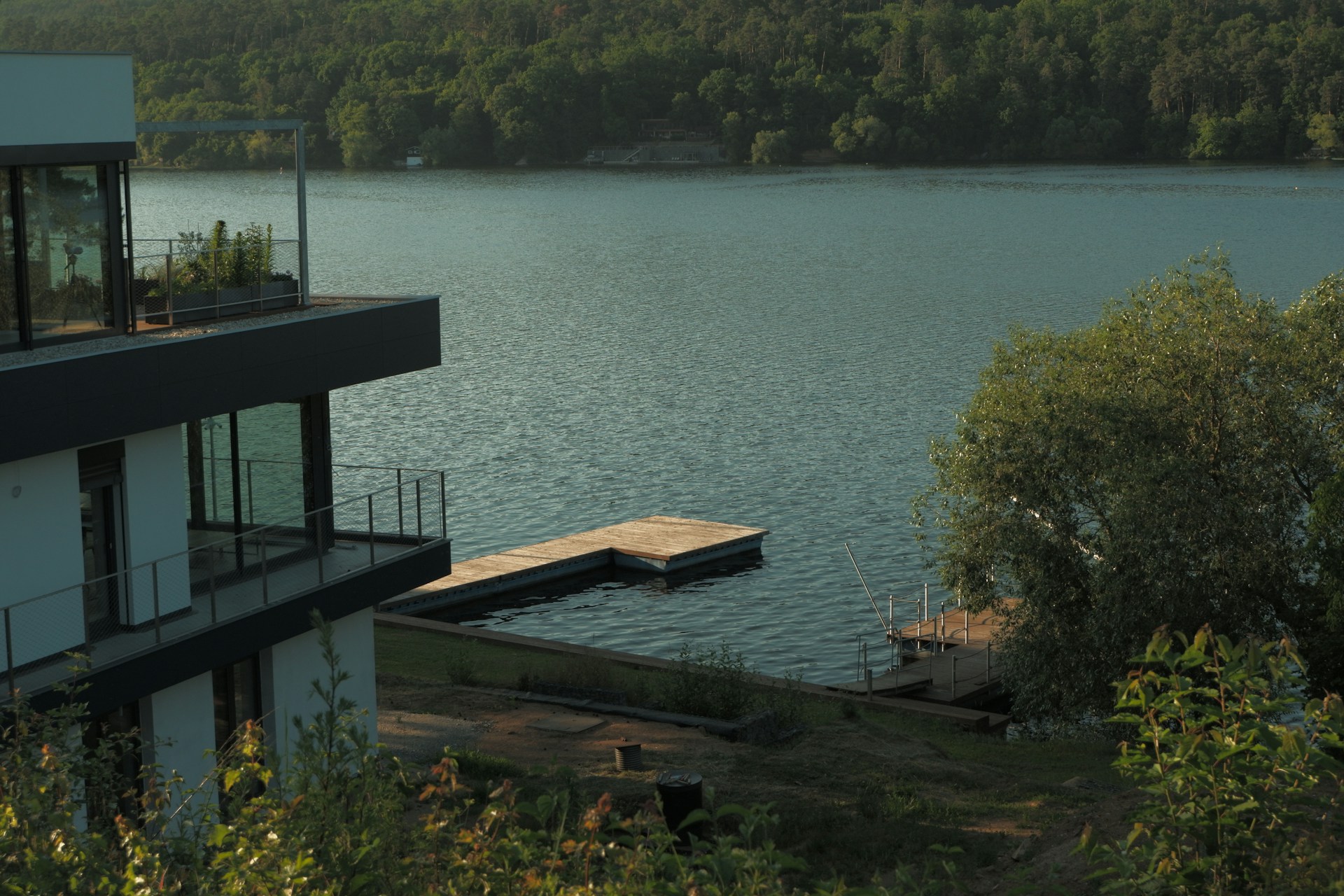 Modern home overlooks a serene lake and dock.