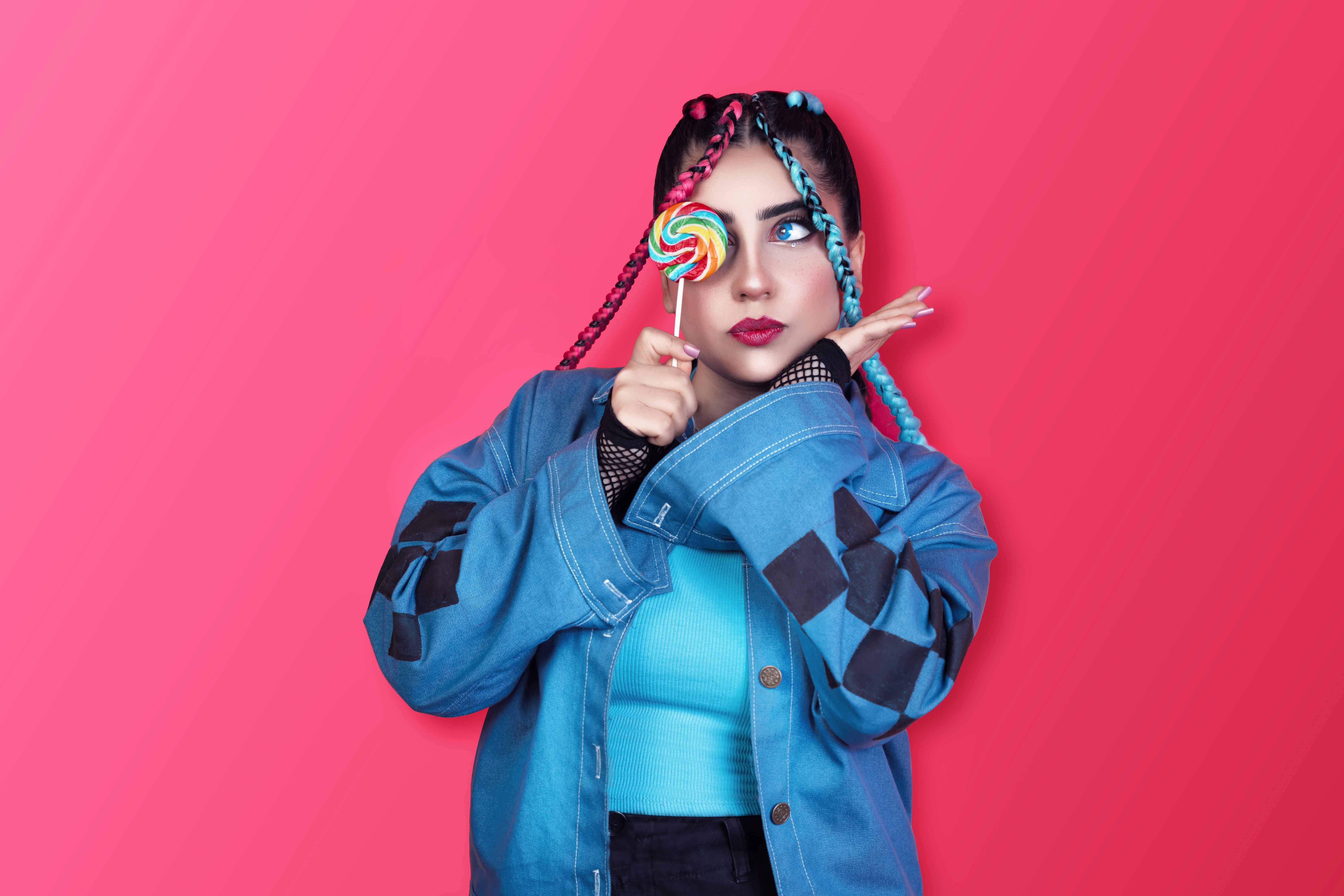 Woman with braids and lollipop poses playfully.