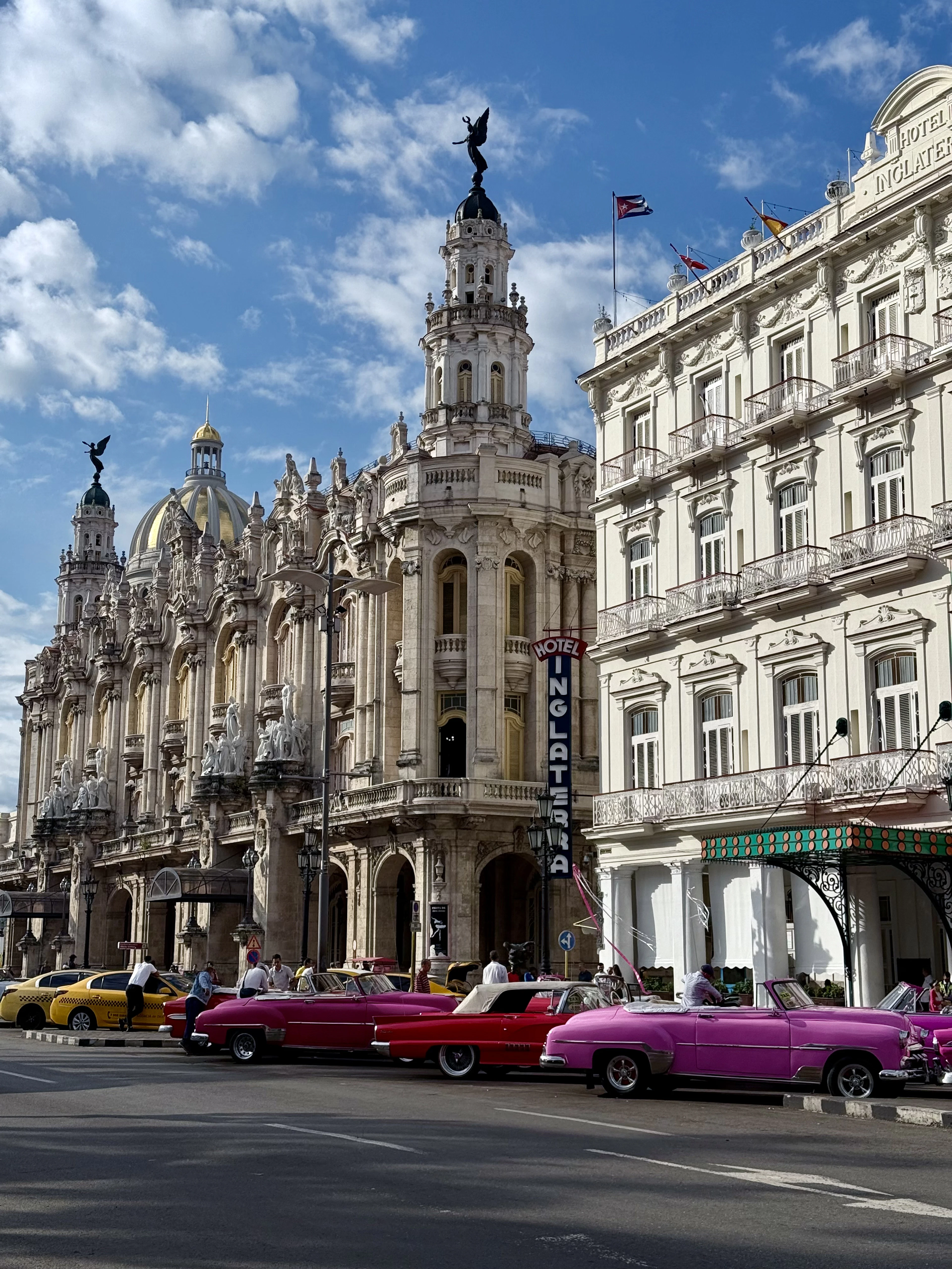 Pink and red 1950s American cars parked outside the Gran Teatro de La Habana and the Hotel Inglaterra