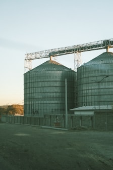 Large metal silos stand tall under a clear sky.