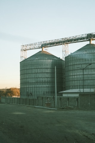 Large metal silos stand tall under a clear sky.