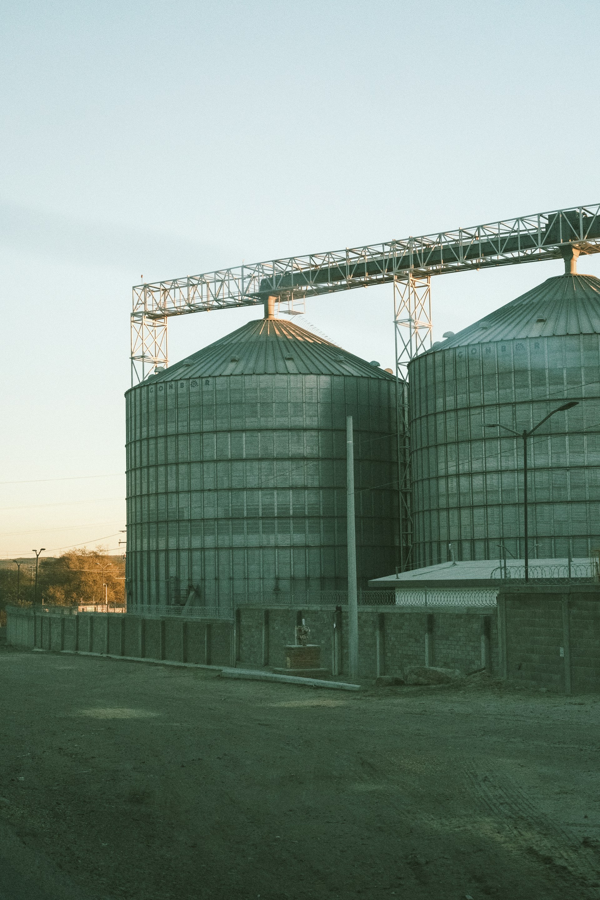 Large metal silos stand tall under a clear sky.