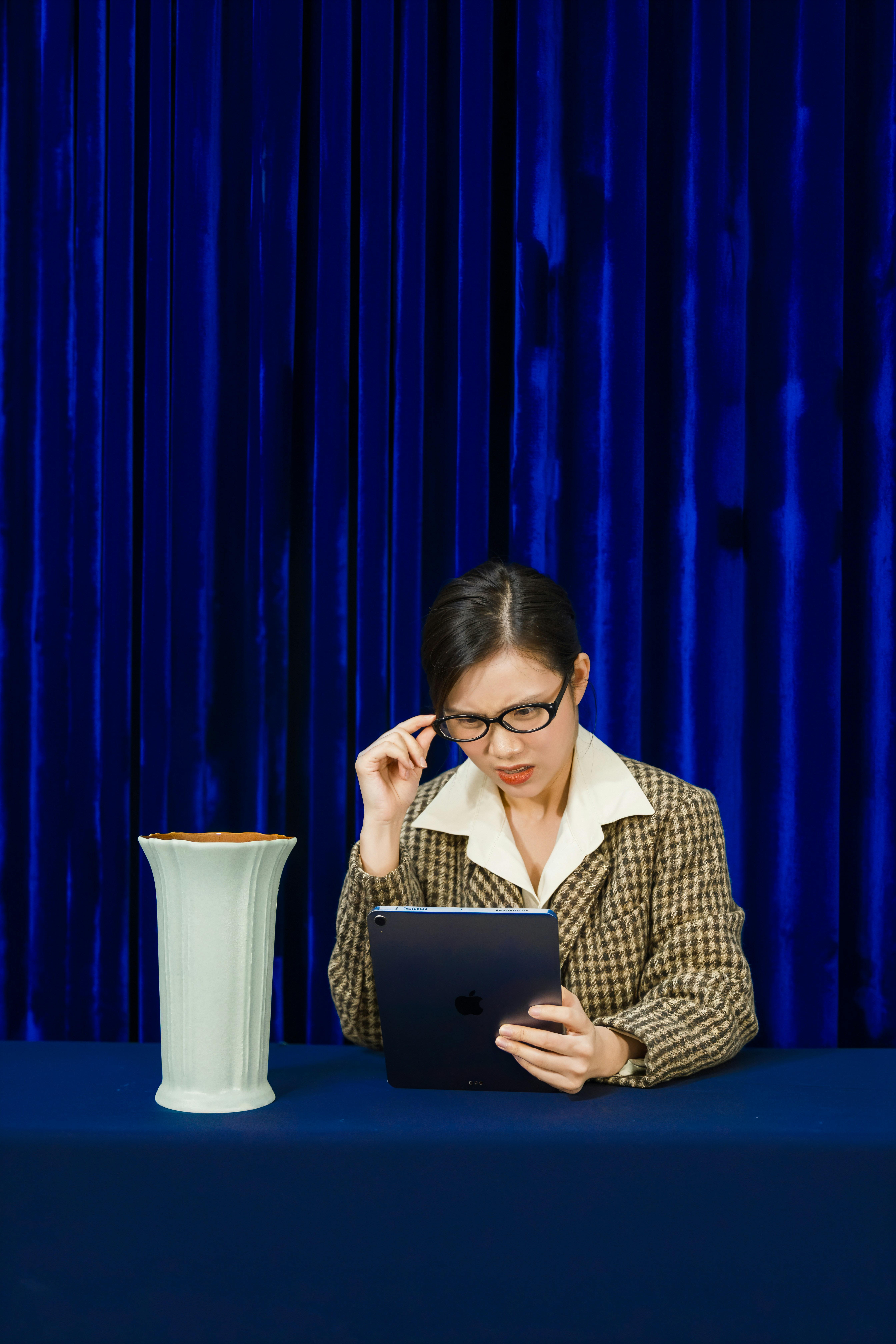 Woman in glasses looking at tablet with vase