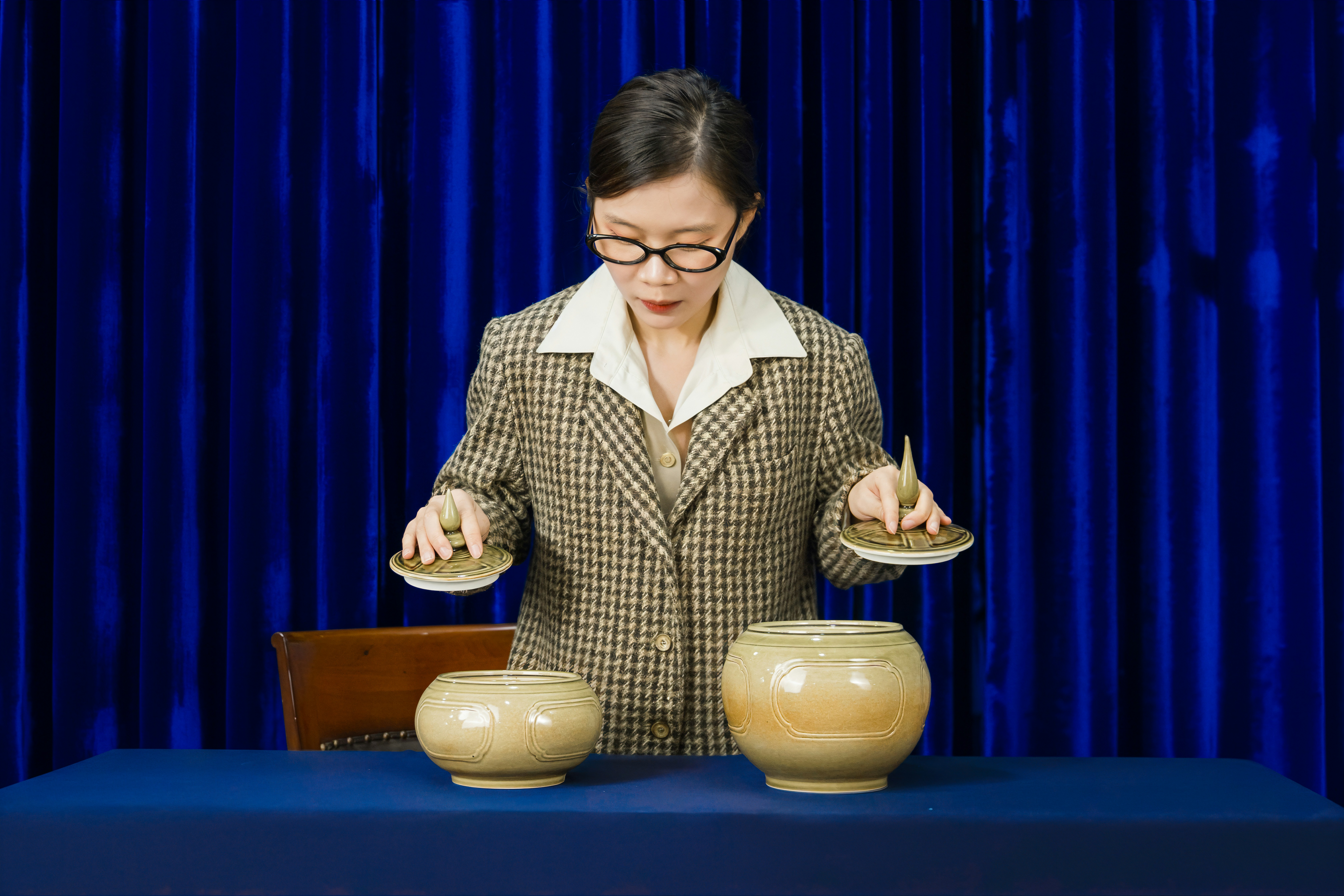 Woman in glasses examines two ceramic pots