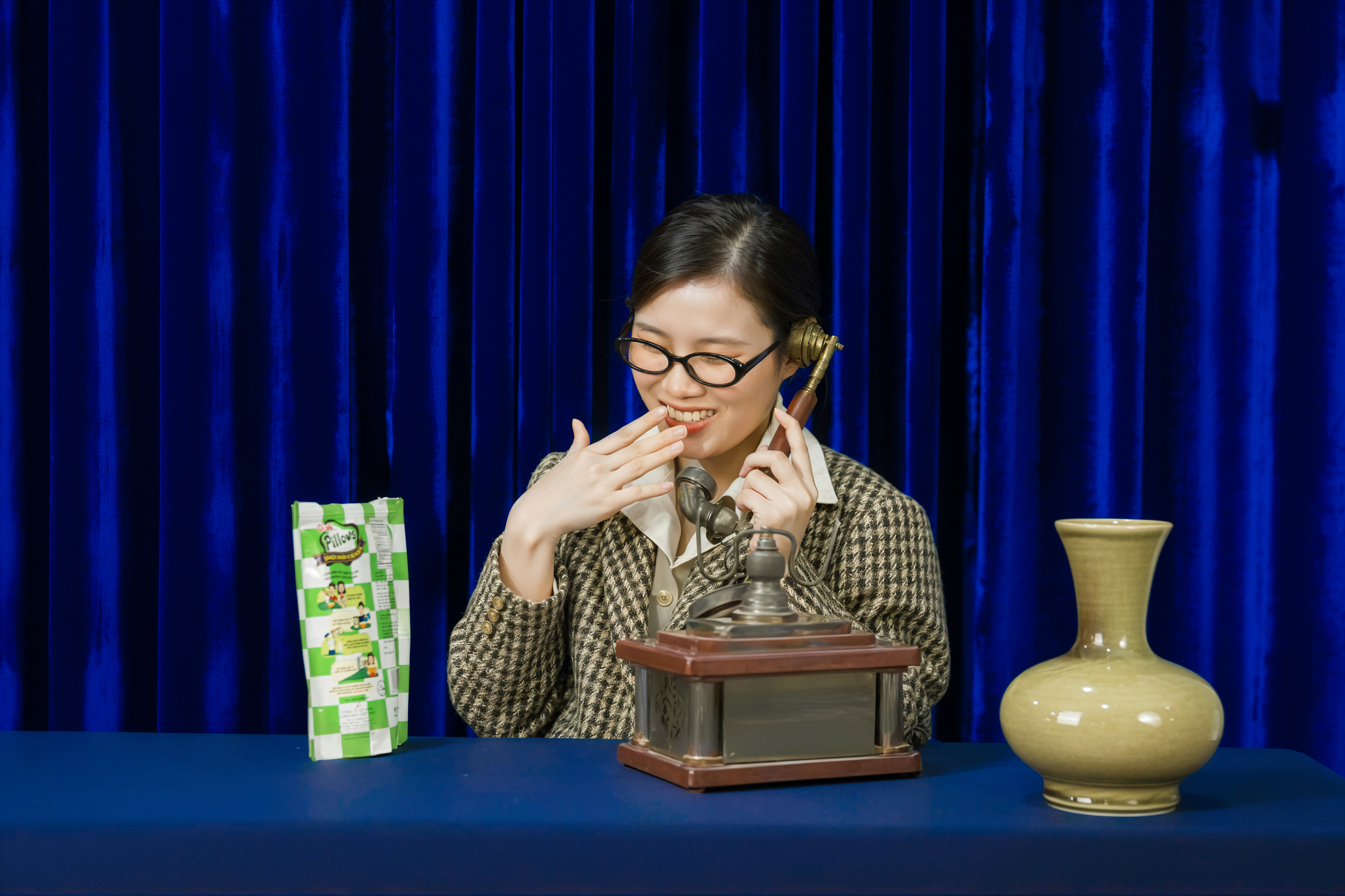 Woman in glasses talks on phone, touches mouth.