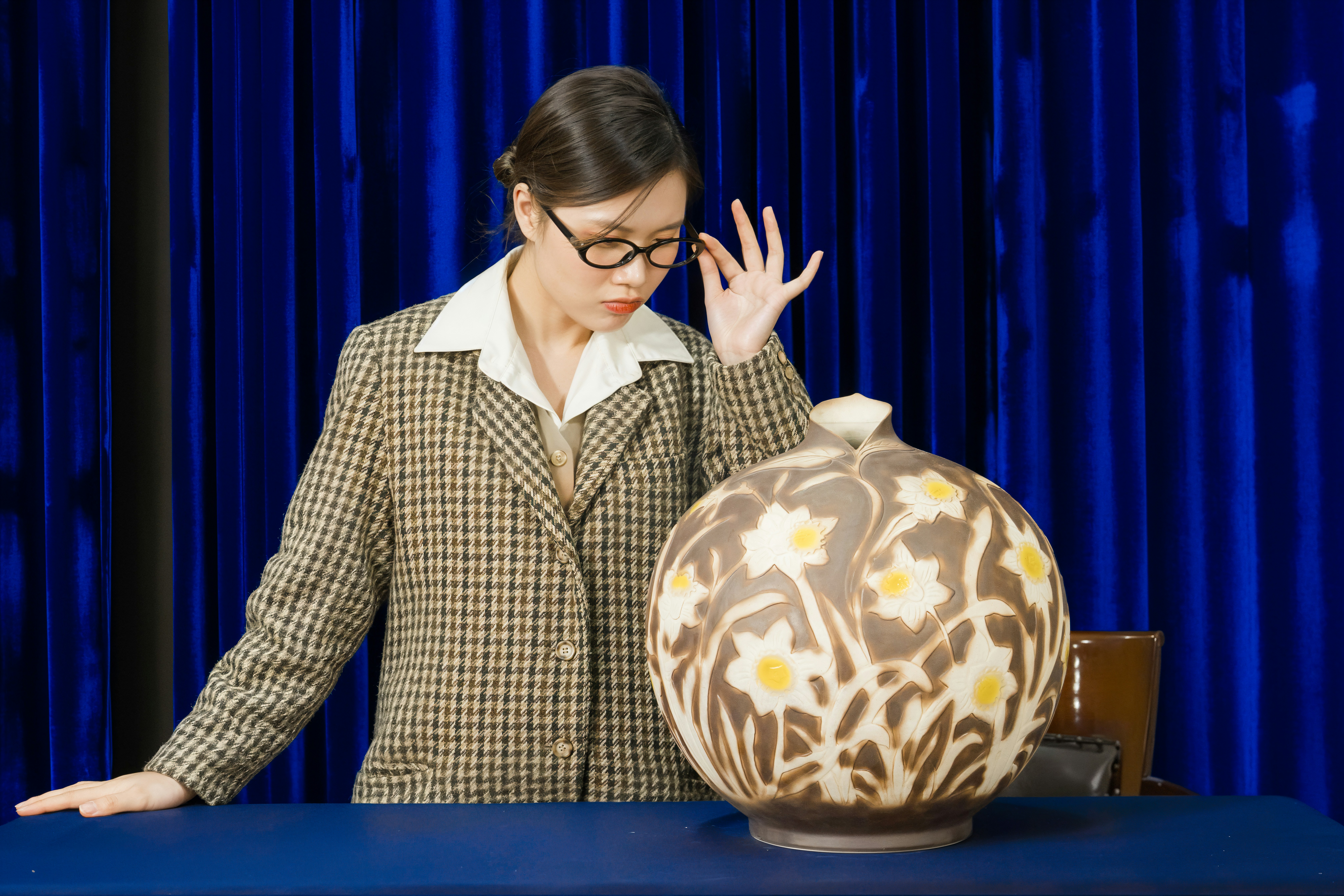 Woman examining a large floral patterned vase
