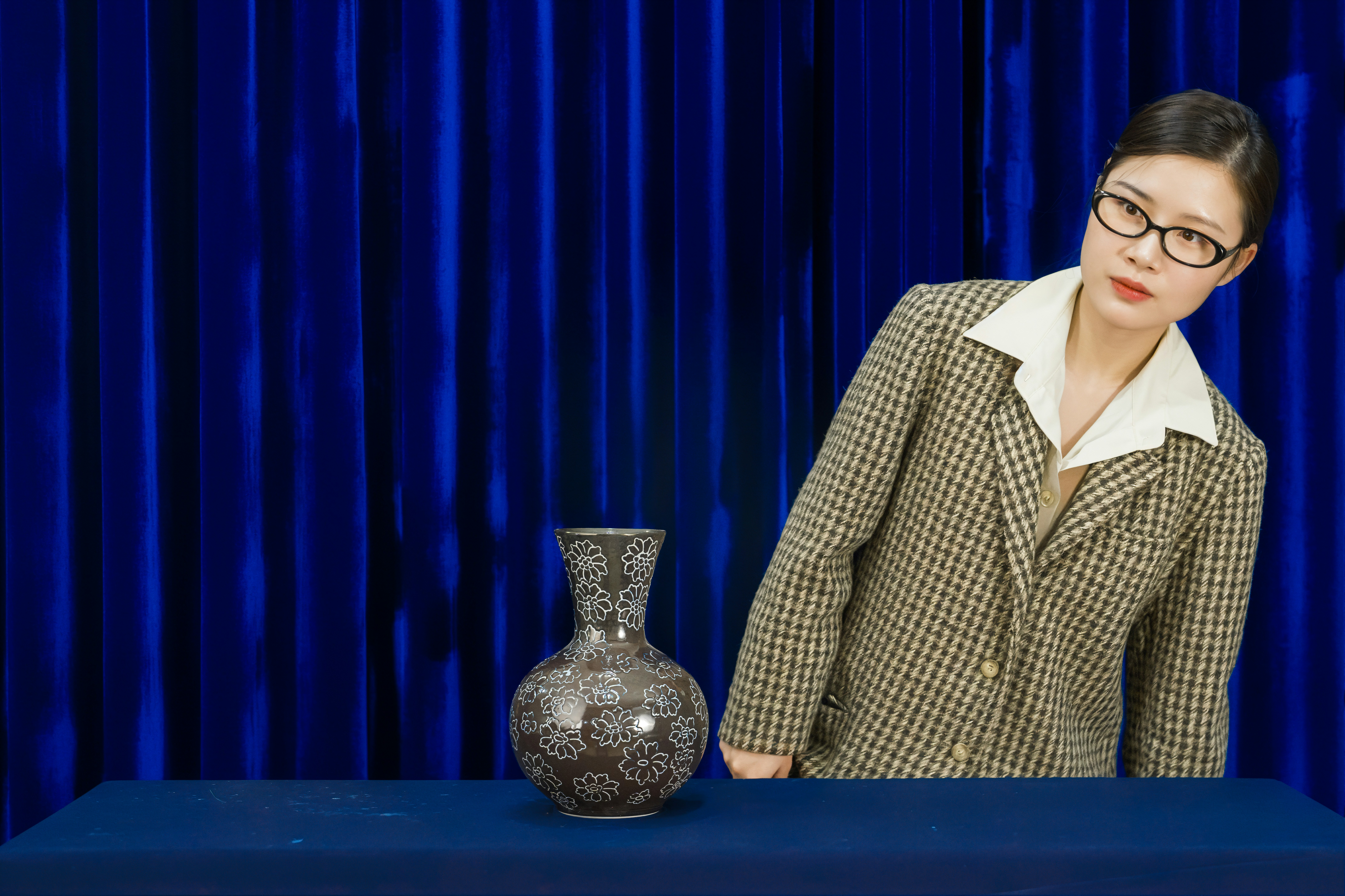 Woman in glasses stands by ornate vase