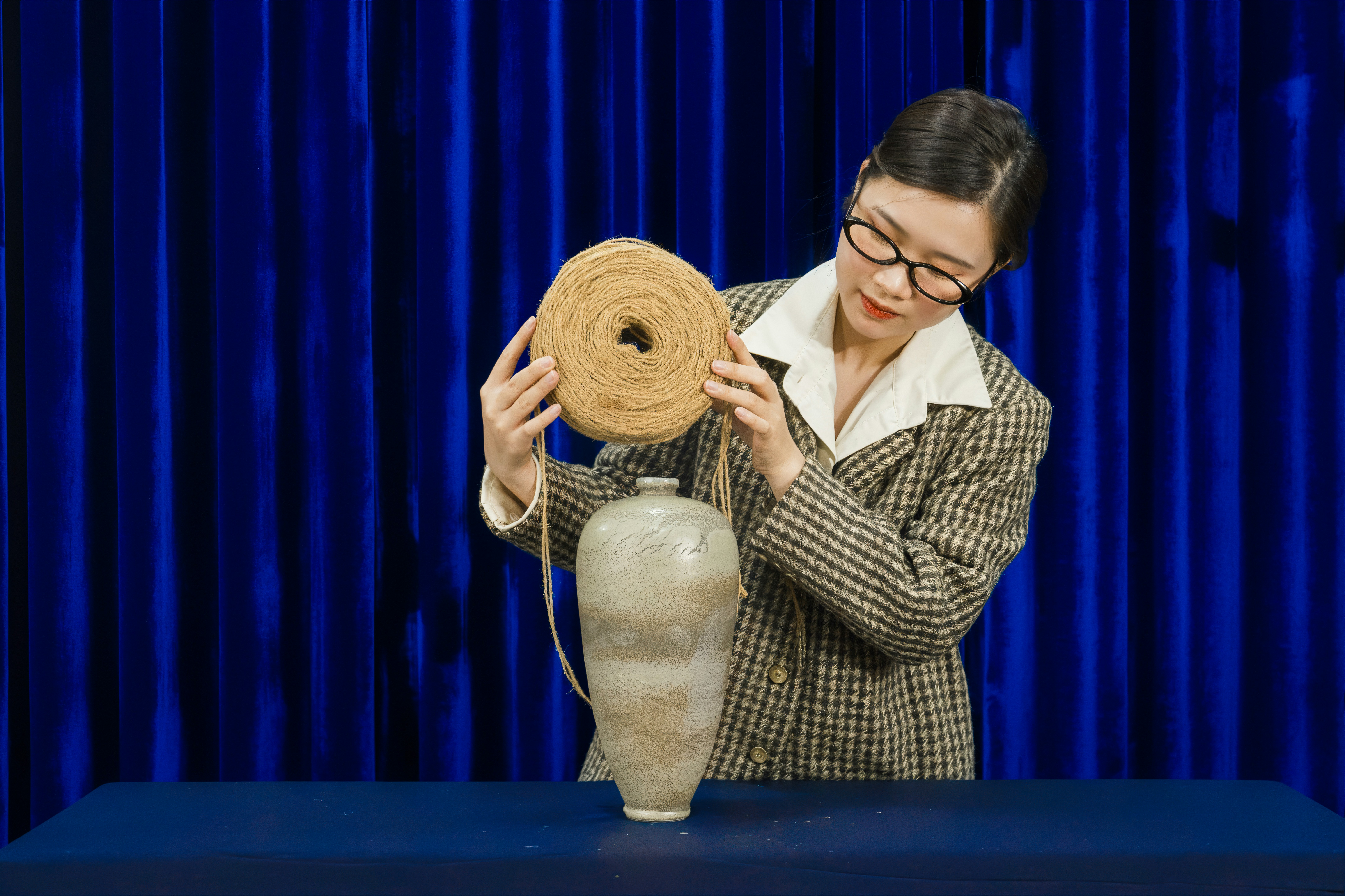 Woman holding a roll of twine over a vase.