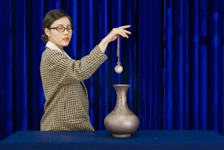 Woman with glasses dangles pendulum over vase