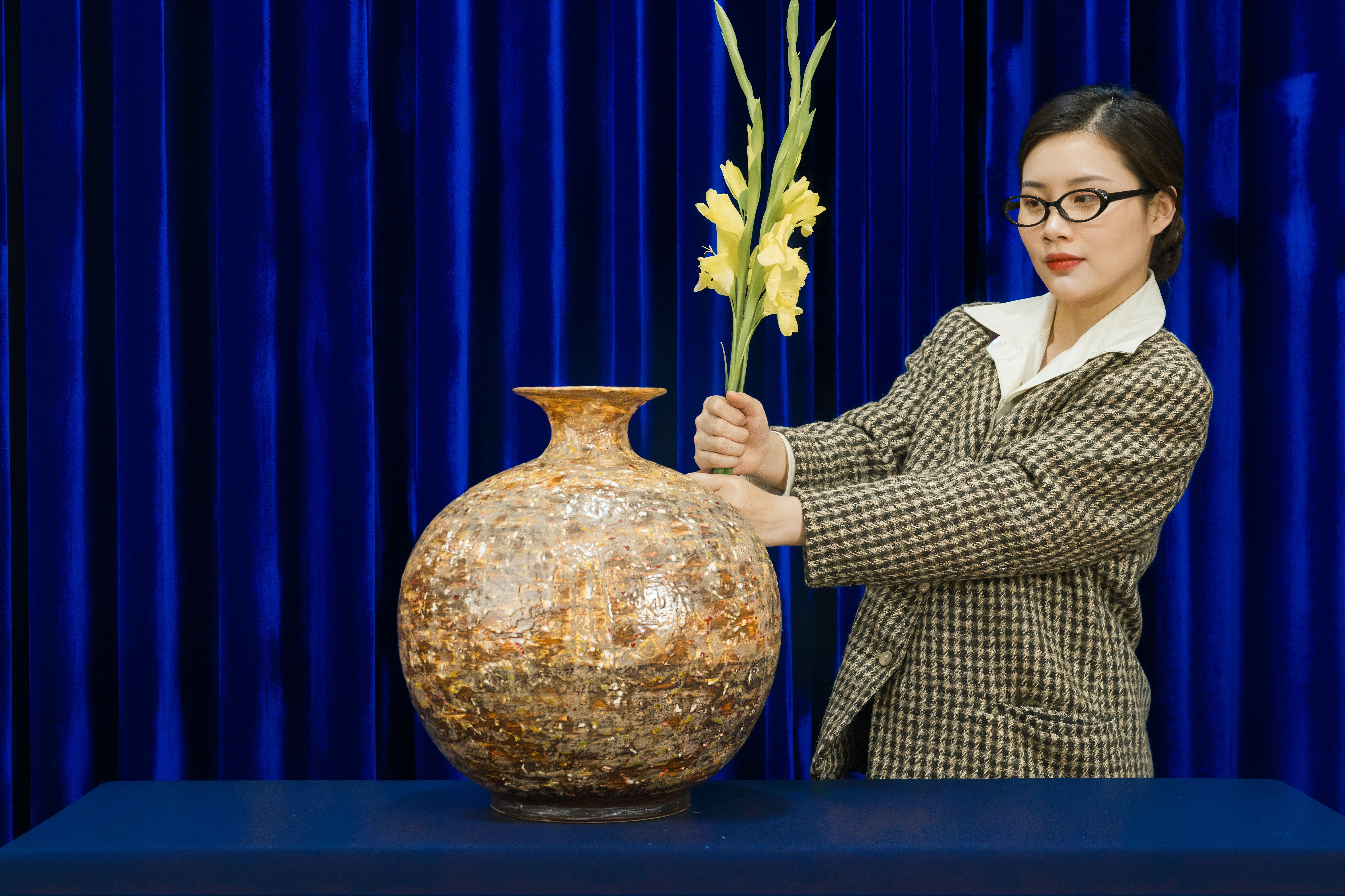 Woman arranging yellow flowers in a large vase
