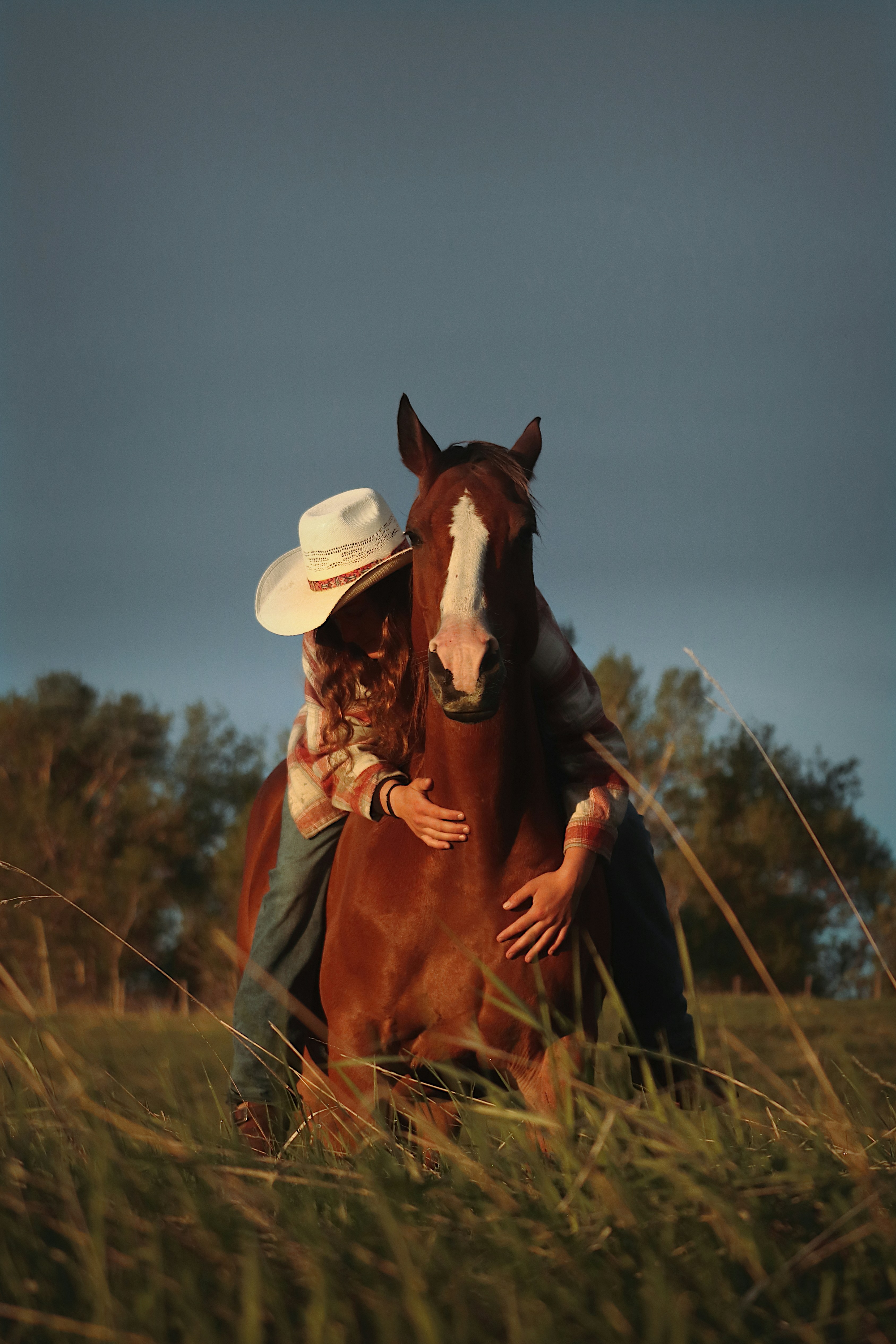 A cowgirl hugs her horse.