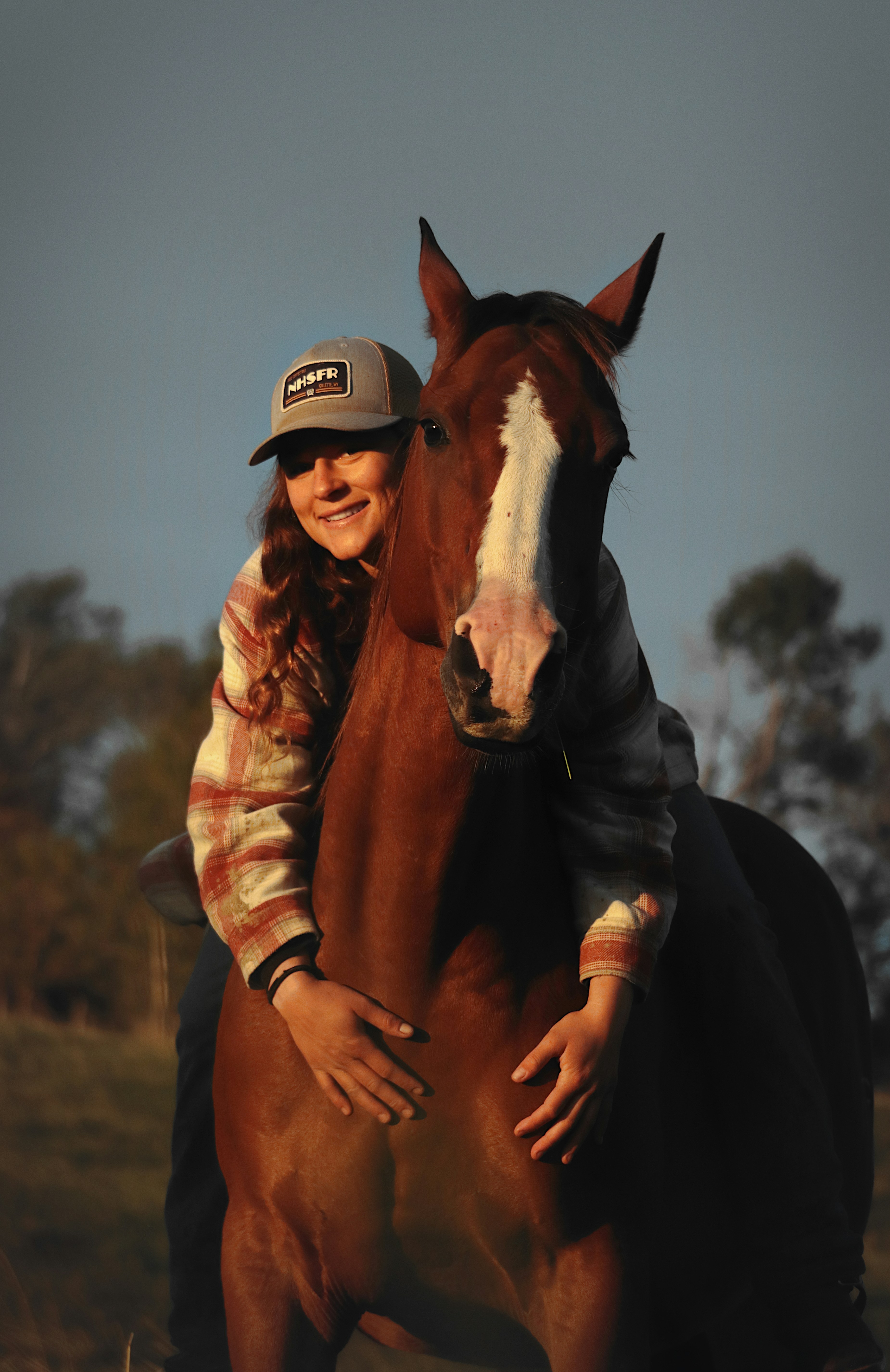 Woman hugs a horse while smiling.