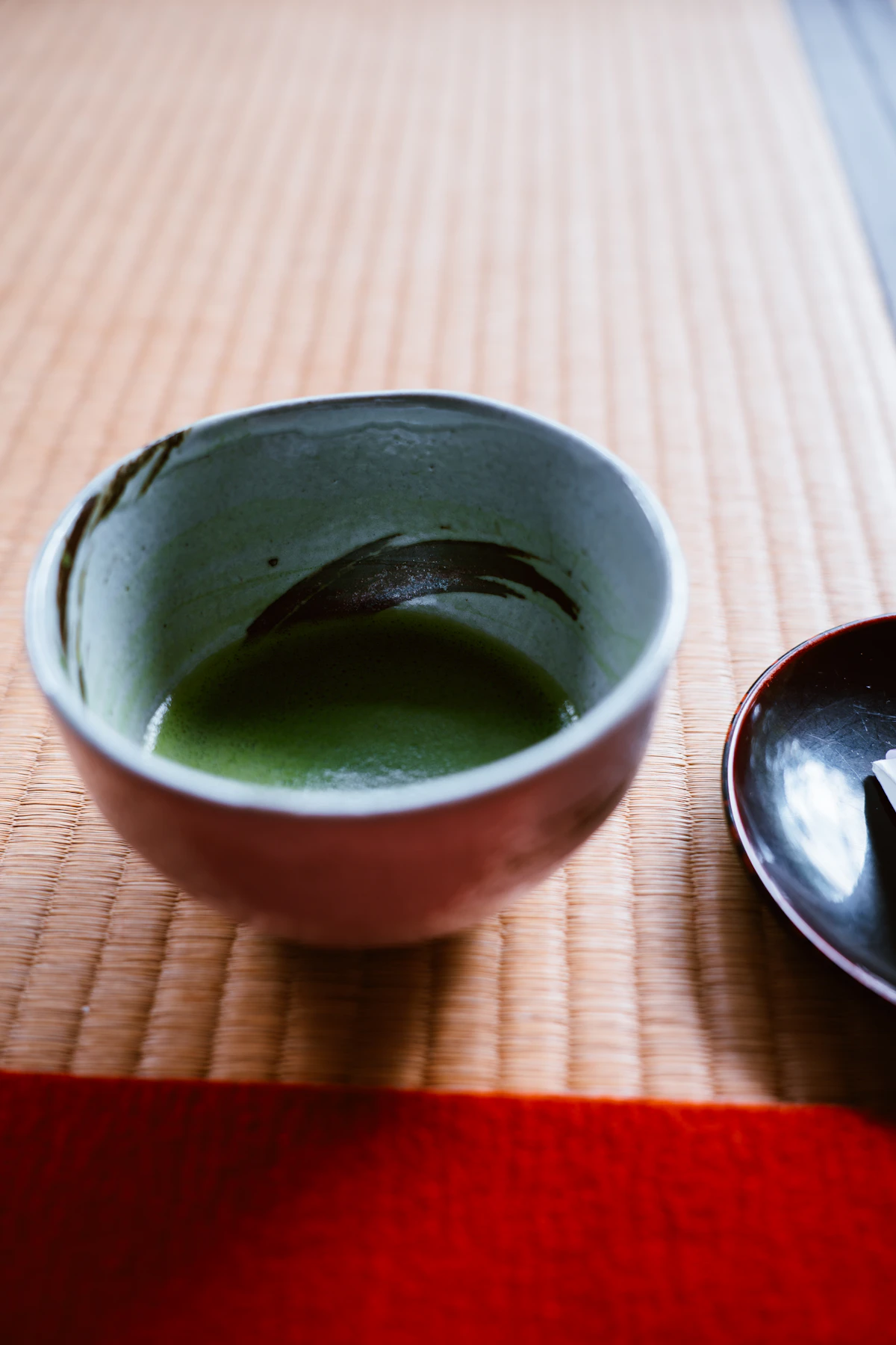 Matcha-Schale mit leuchtend grünem Pulver auf einem Bambus-Tablett, traditionelle Zubereitung