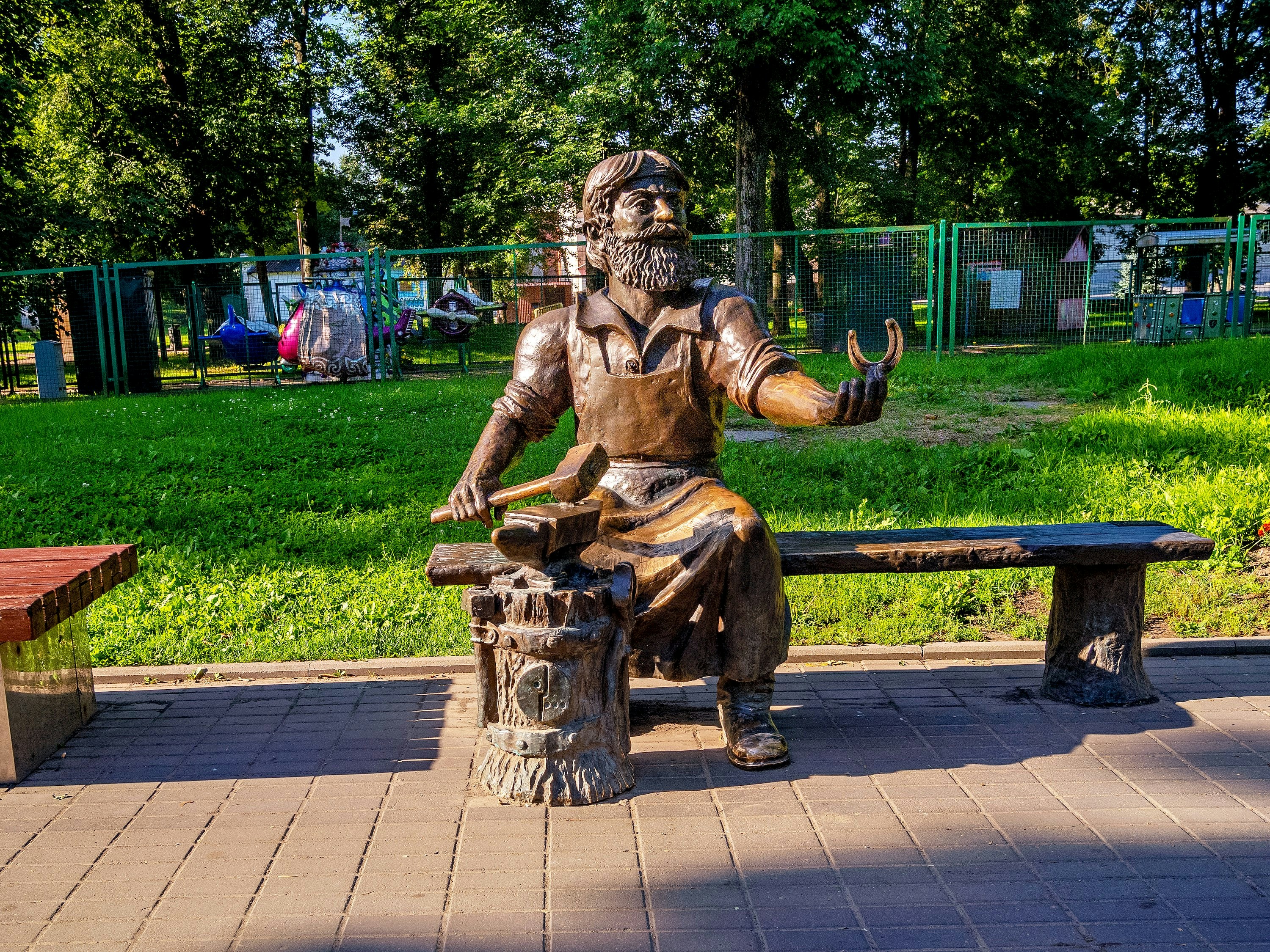 A statue of a blacksmith sits on a bench.