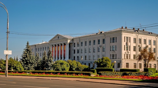 Large, white building with columns and a manicured lawn.