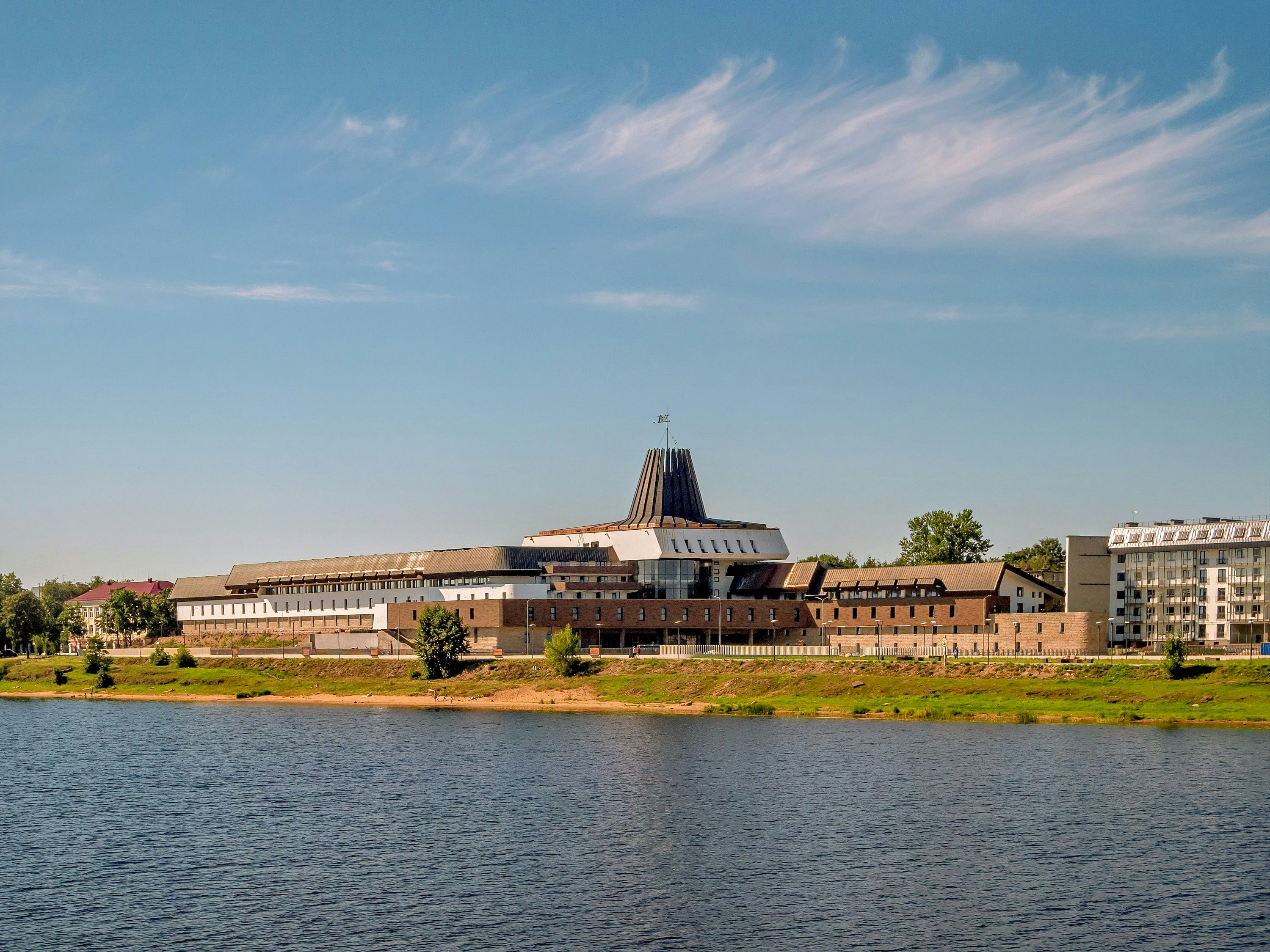 A modern building sits along a calm river.