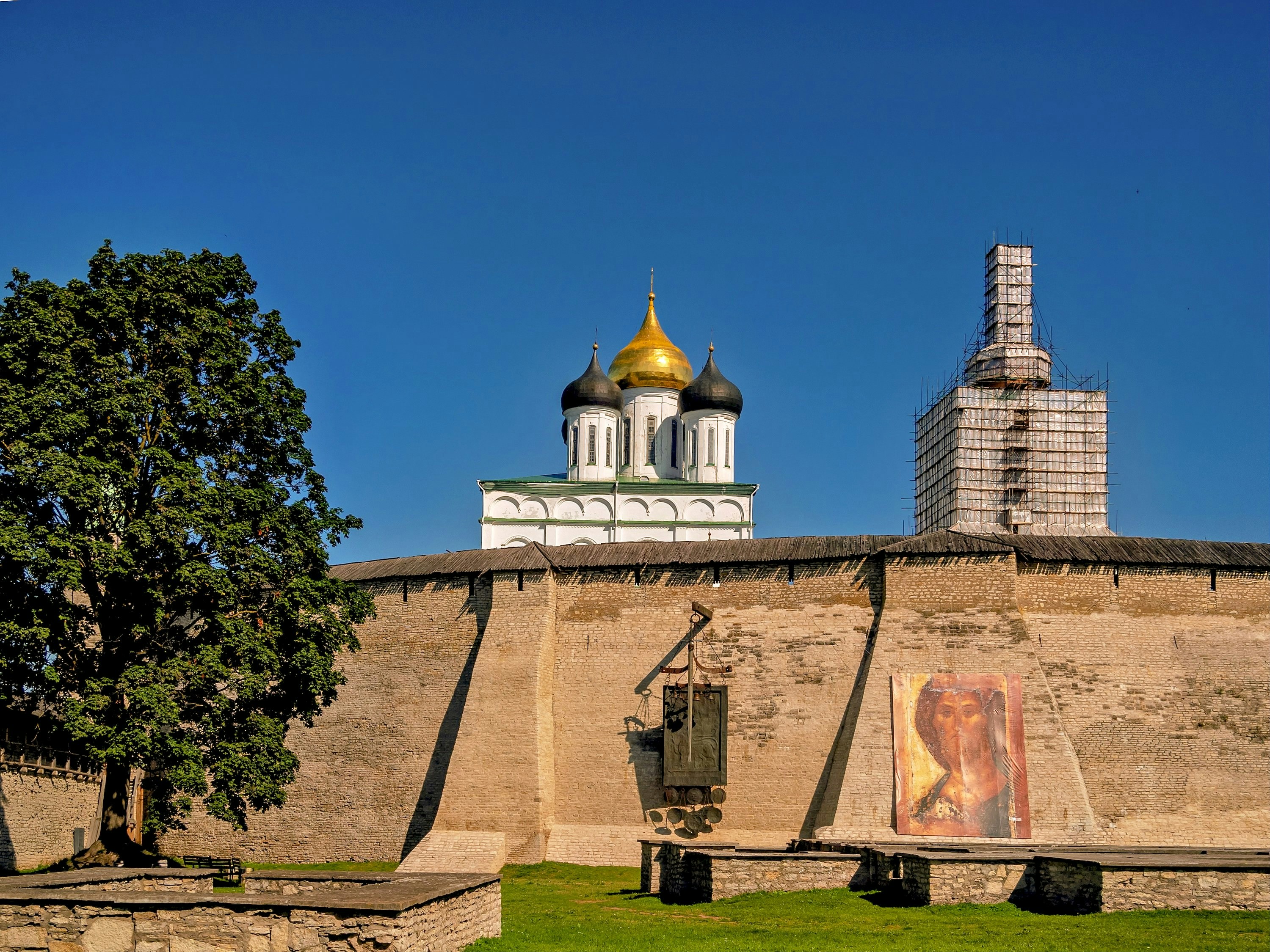 An orthodox church is behind a stone wall.