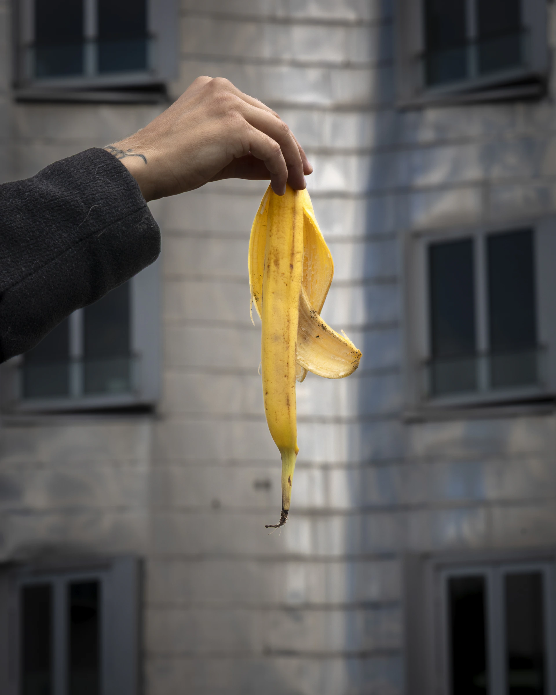 A hand holds up a banana peel.