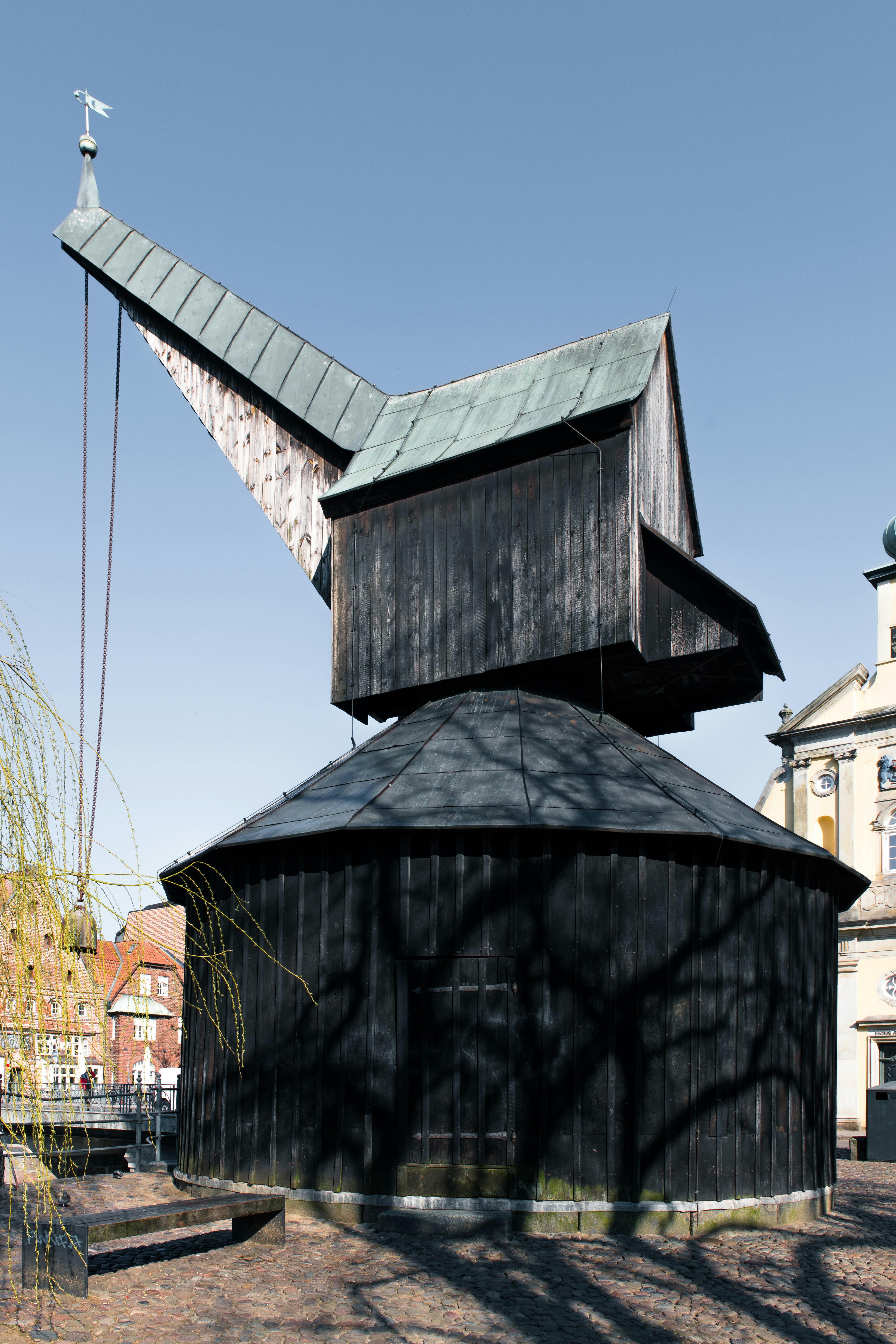 An old wooden crane stands tall in the sunlight.
